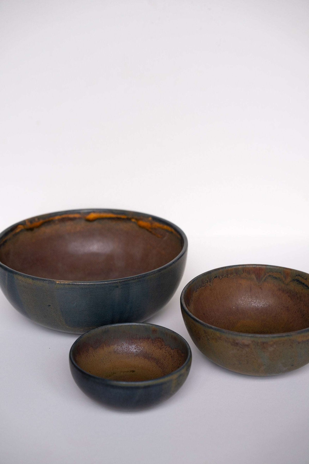 Rust stoneware nesting bowl set with matte brown-black glaze and subtle swirls, handmade in Ukraine