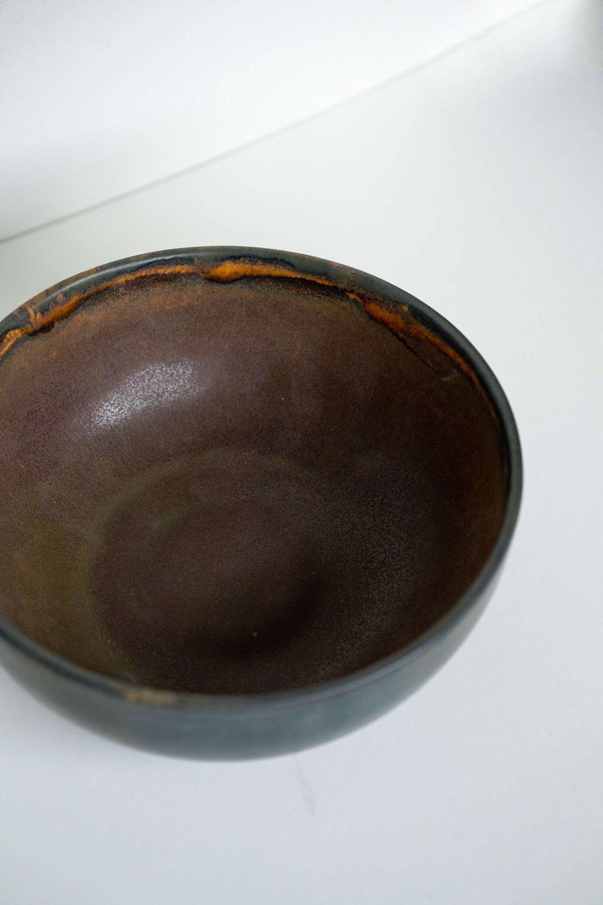 Rust stoneware nesting bowl set with matte brown-black reactive glaze and unique swirls