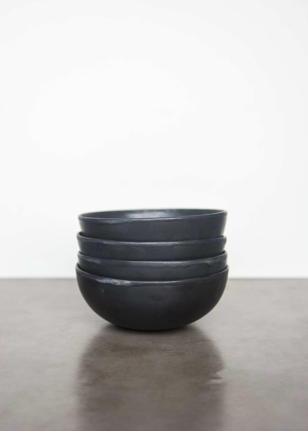 Black matte stoneware bowl with organic curves and lighter rim, handmade in Ukraine