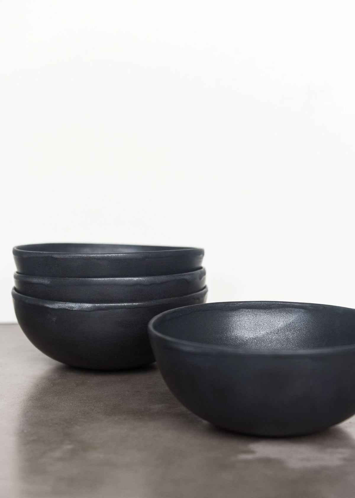 Black matte stoneware bowl with organic curves and lighter rim, handmade in Ukraine, food-safe and dishwasher-safe.