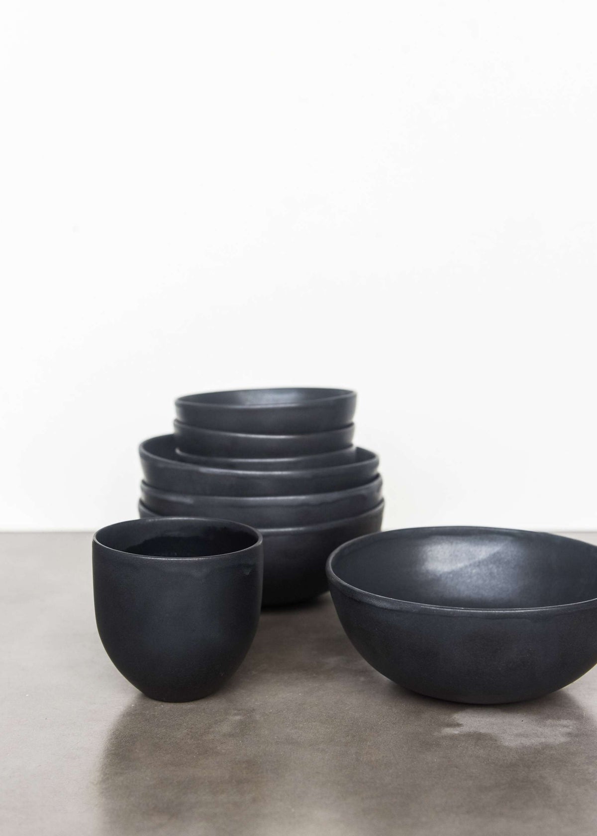 Handmade black matte stoneware bowl with organic curves and lighter rim, food-safe and dishwasher safe