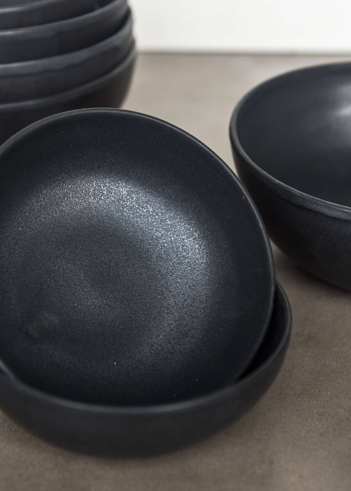 Black matte stoneware bowl with organic curves and lighter rim, handmade in Ukraine