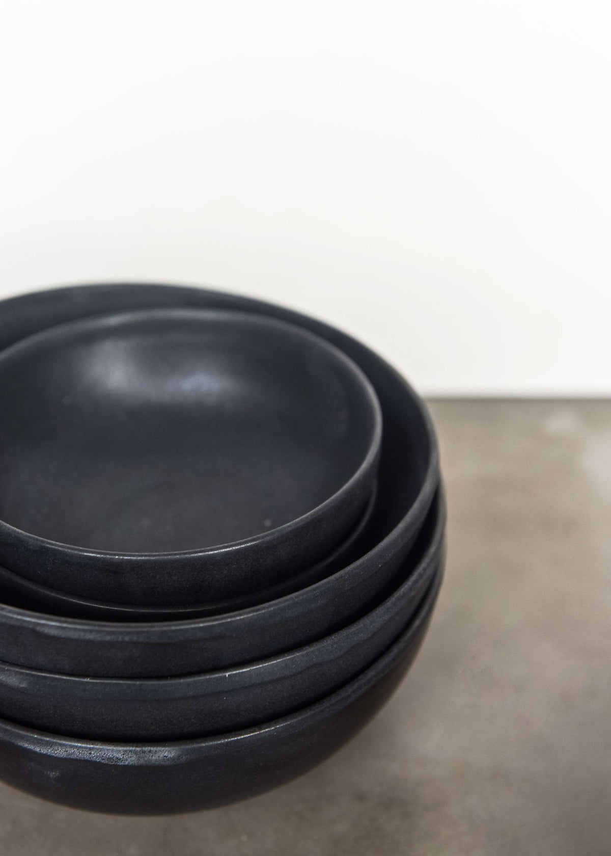 Black matte stoneware bowl with organic curves and lighter rim, handmade in Ukraine