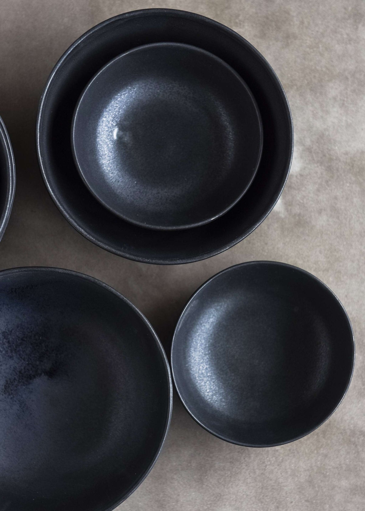 Handmade black matte stoneware bowl with organic curves and lighter rim, food-safe and microwave safe.