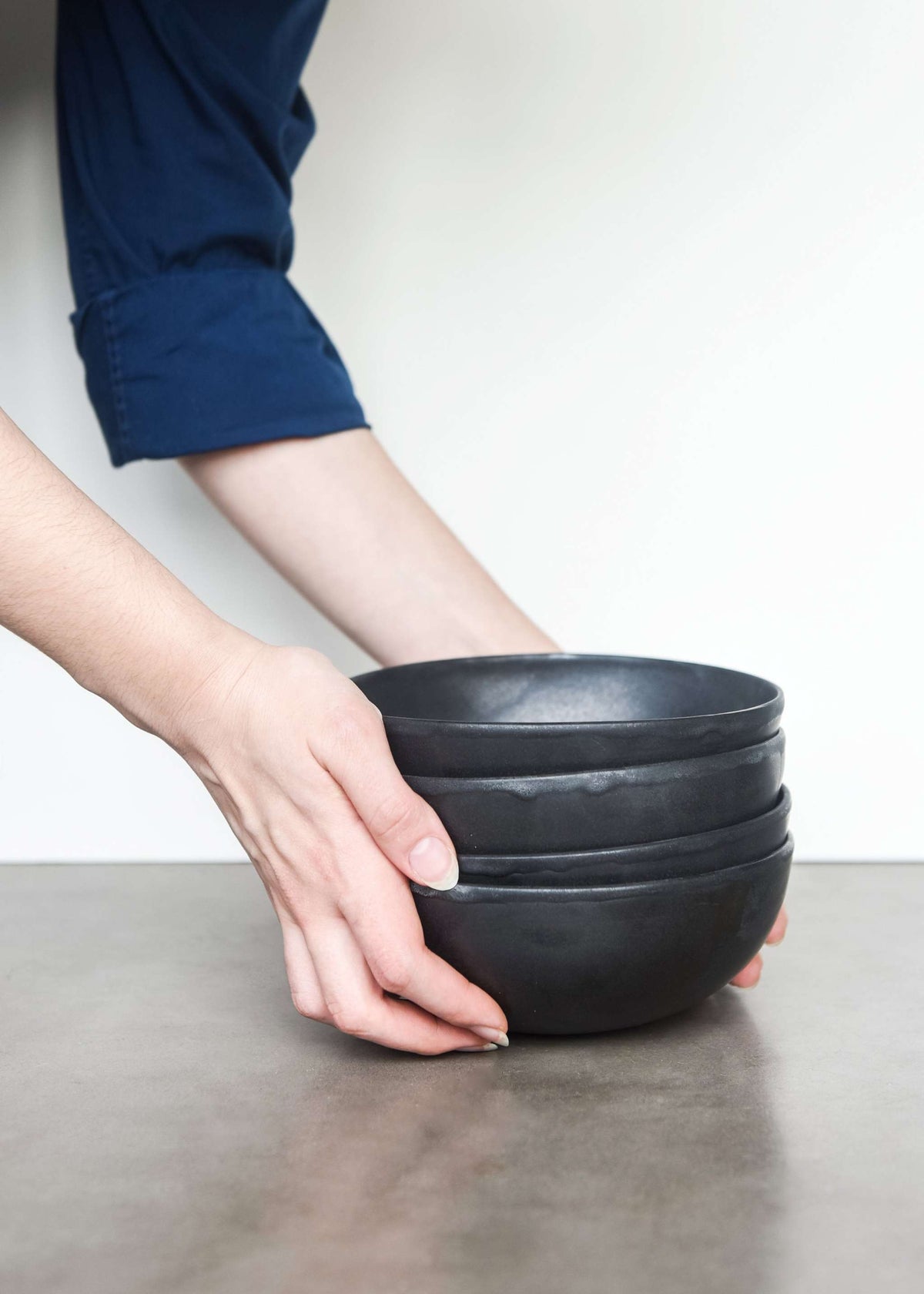 Handmade black matte stoneware bowl with organic curves and lighter rim, food-safe and dishwasher-safe.