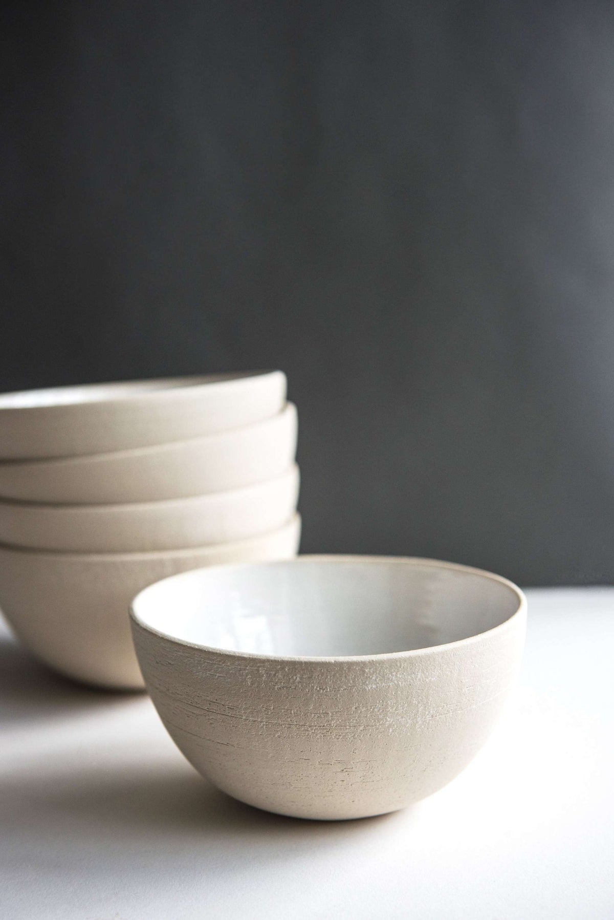 Handmade stoneware soup bowl with white glazed interior and rough exterior texture