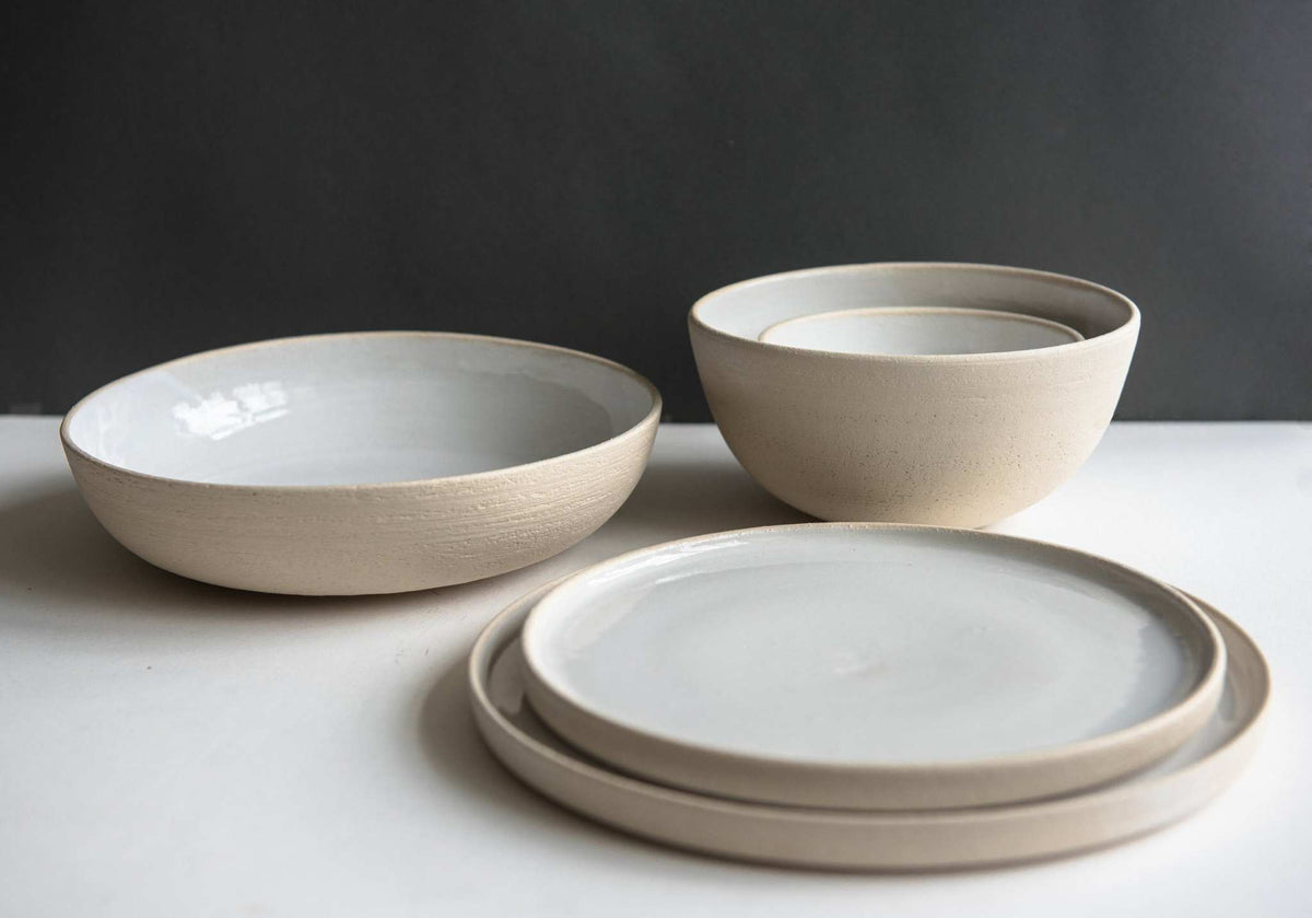 Stoneware Pasta Bowl with a smooth white glazed interior and matte beige exterior, shown with matching bowl and plates.