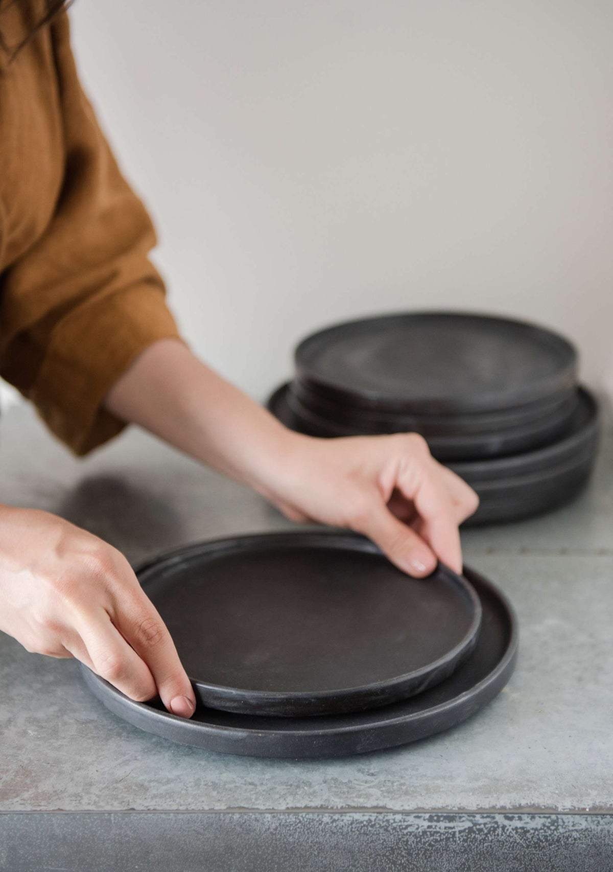 Handmade black matte stoneware dinner plate with textured glaze and light border ring