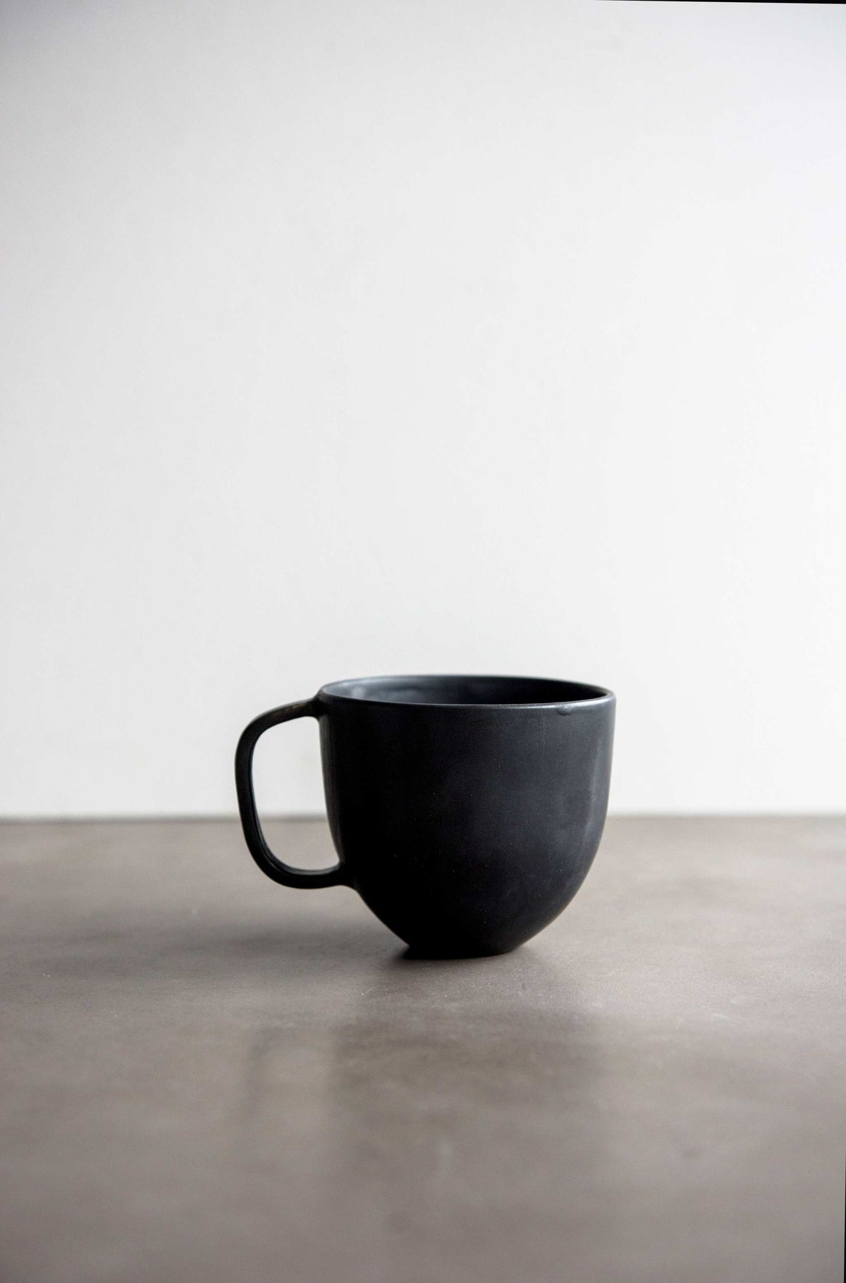 Handcrafted black matte stoneware coffee mug with reactive glaze and comfortable handle