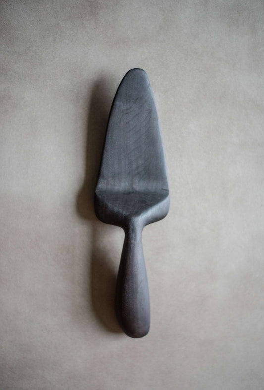 Hand-carved charred alder wood cake server with smooth handle and natural grain finish