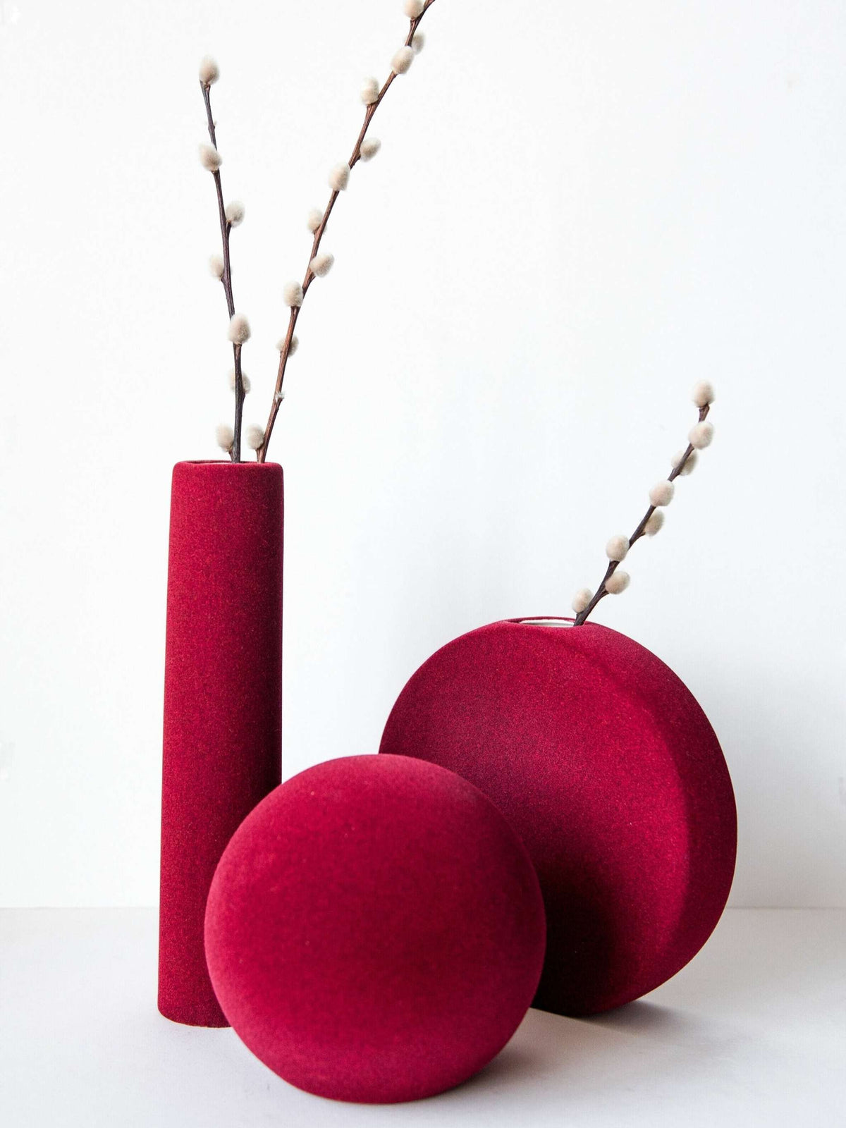 Porcelain set of home decor with burgundy geometric vases including tall tube vase, round vase, and sphere