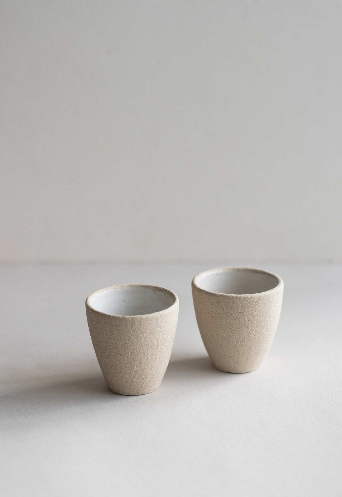Handmade stoneware espresso cup with exposed clay exterior and white glazed interior, dishwasher and microwave safe
