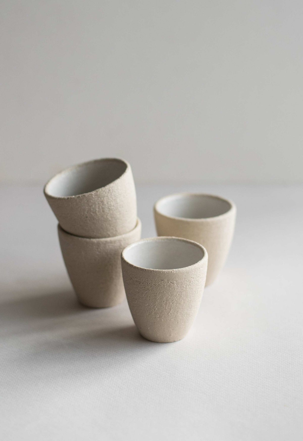 Handmade stoneware espresso cup with exposed clay exterior and white glaze interior, dishwasher-safe and lead-free.