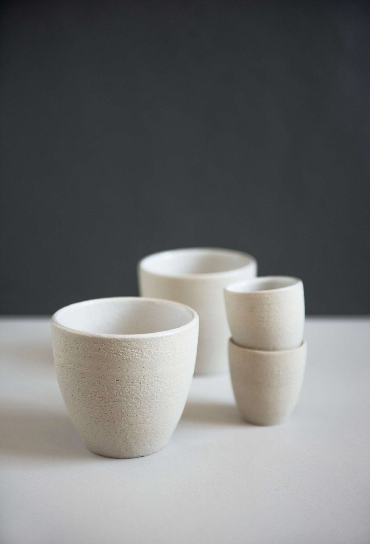 Handmade stoneware coffee cup with rough exterior and white glazed interior, crafted in Ukraine