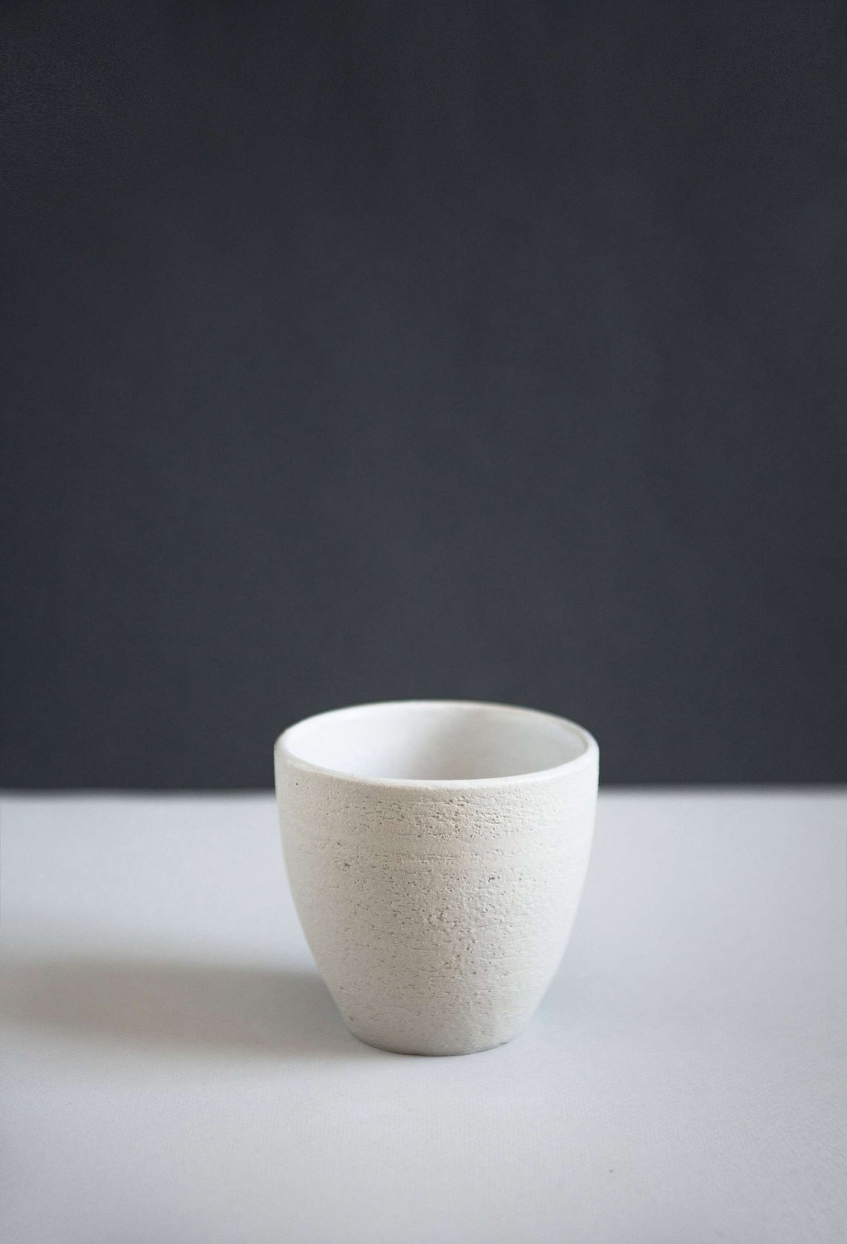 Handmade stoneware coffee cup with textured exterior and white glazed interior, crafted in Ukraine
