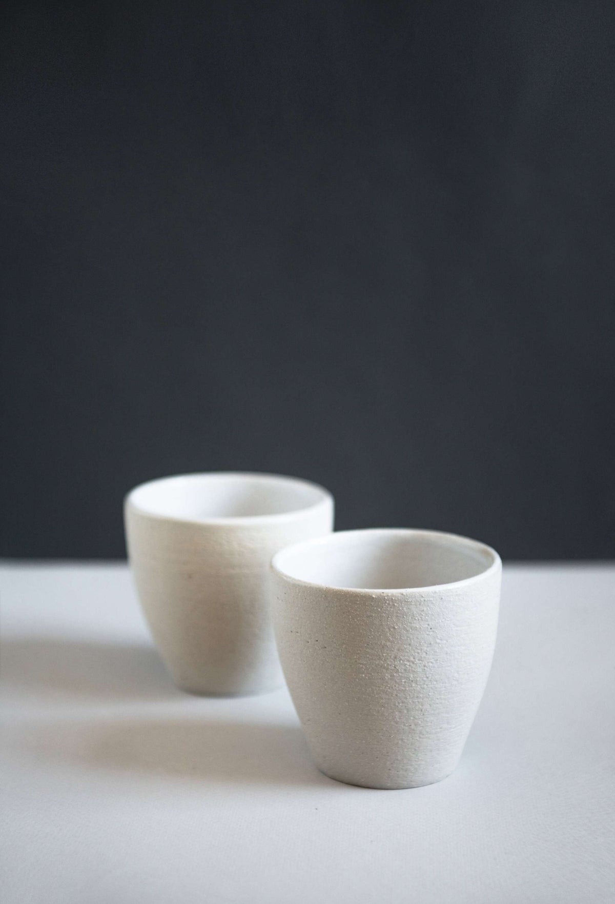 Handmade stoneware coffee cup with rough exterior and white glazed interior, crafted in Ukraine