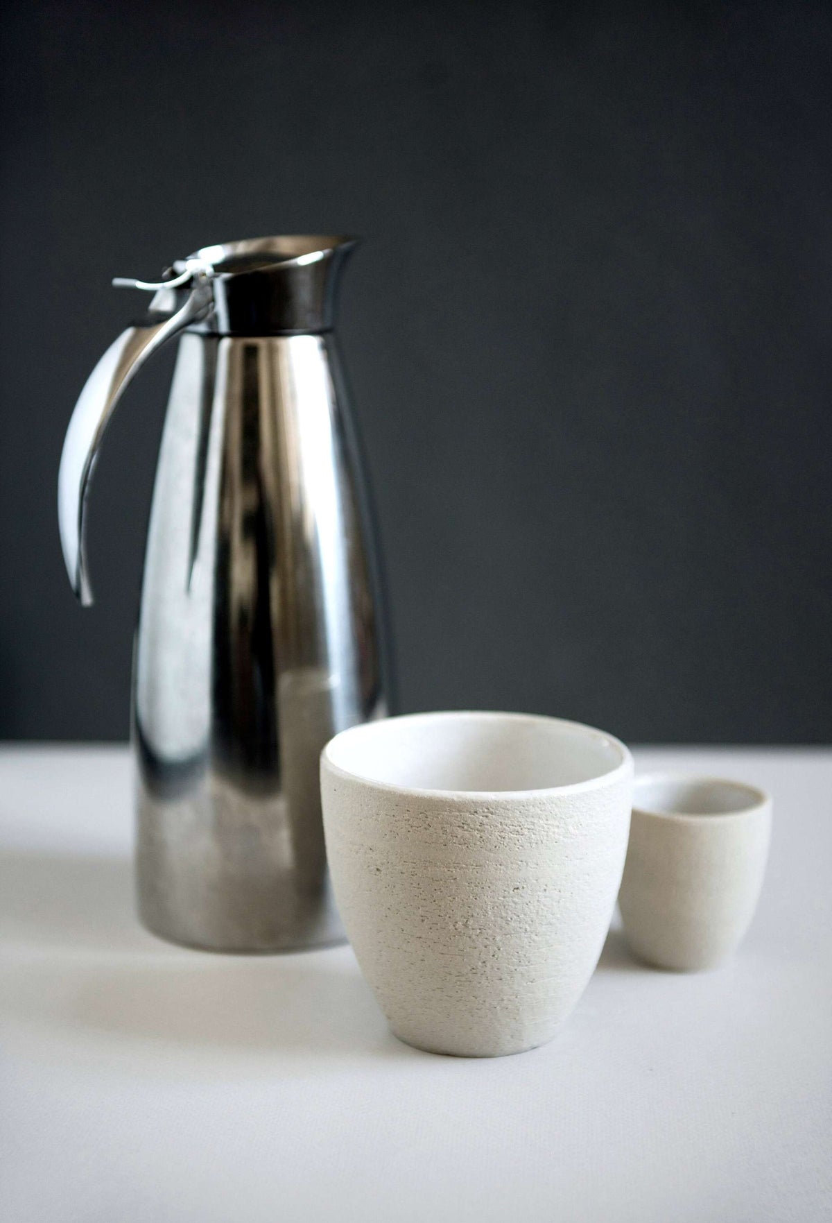 Handmade stoneware coffee cup with rough exterior and white glazed interior, crafted in Ukraine, dishwasher and microwave safe