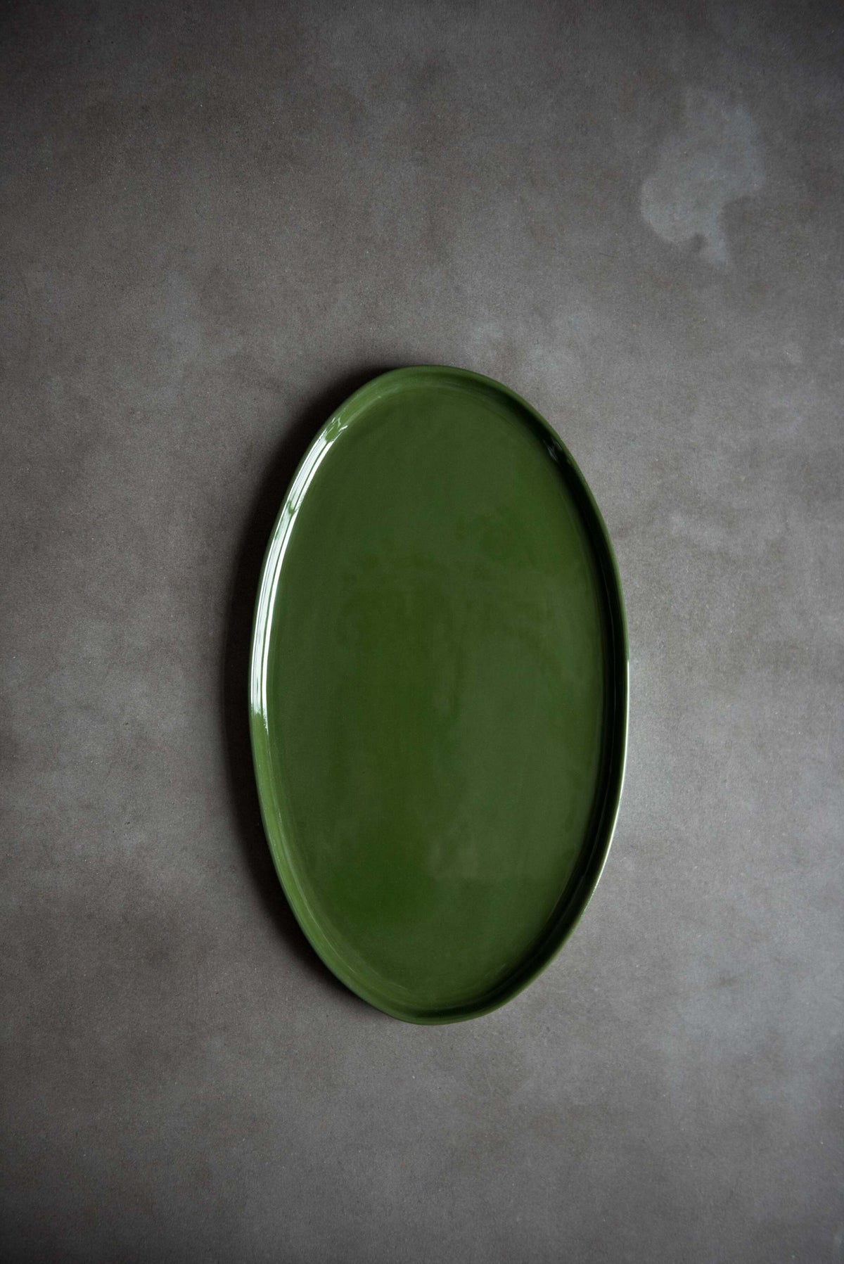 Handmade green oval porcelain platter with organic rounded edges for elegant serving