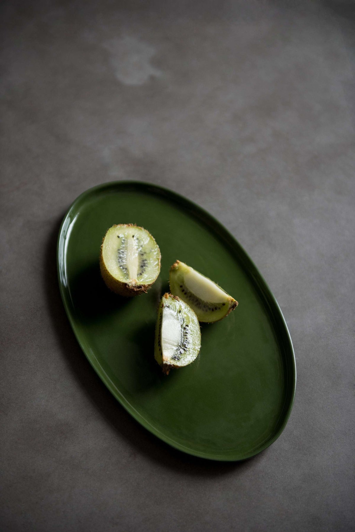 Handmade green oval porcelain platter with organic edges for elegant serving and sustainable use