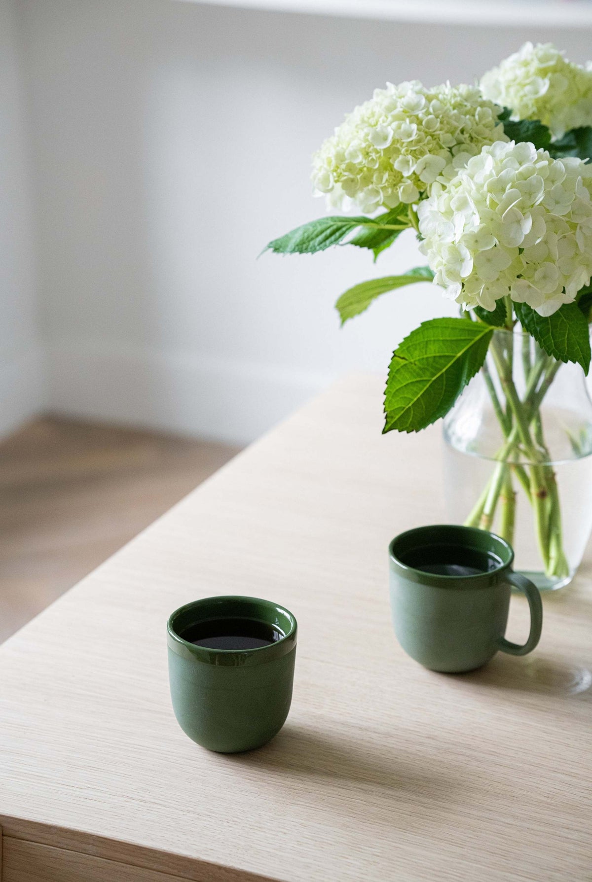Handmade green porcelain coffee cup with shiny glaze, polished exterior, and unique color variations.