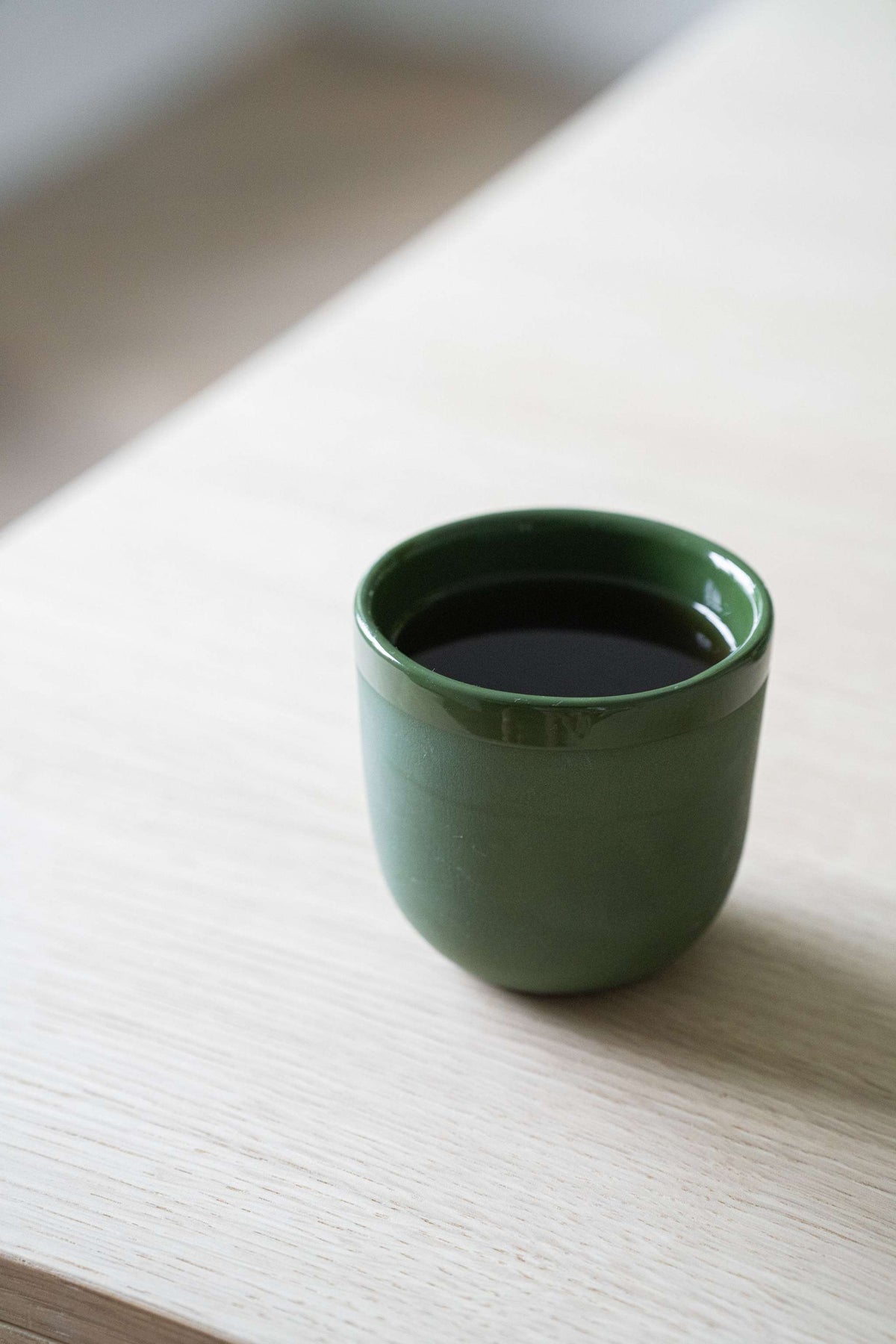 Handmade green porcelain coffee cup with shiny glaze and smooth finish