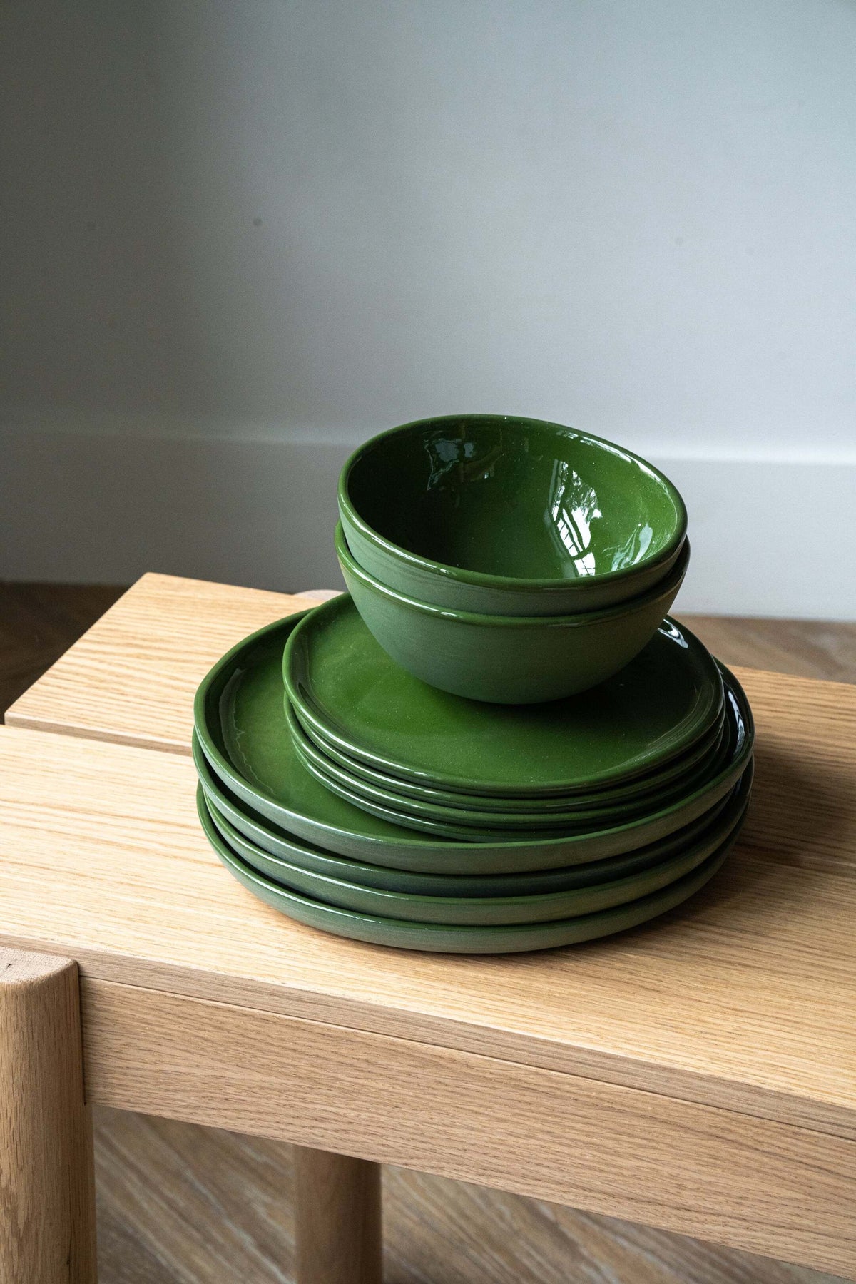Set of handmade porcelain dinner plates in green with shiny glaze, including dinner and salad plates