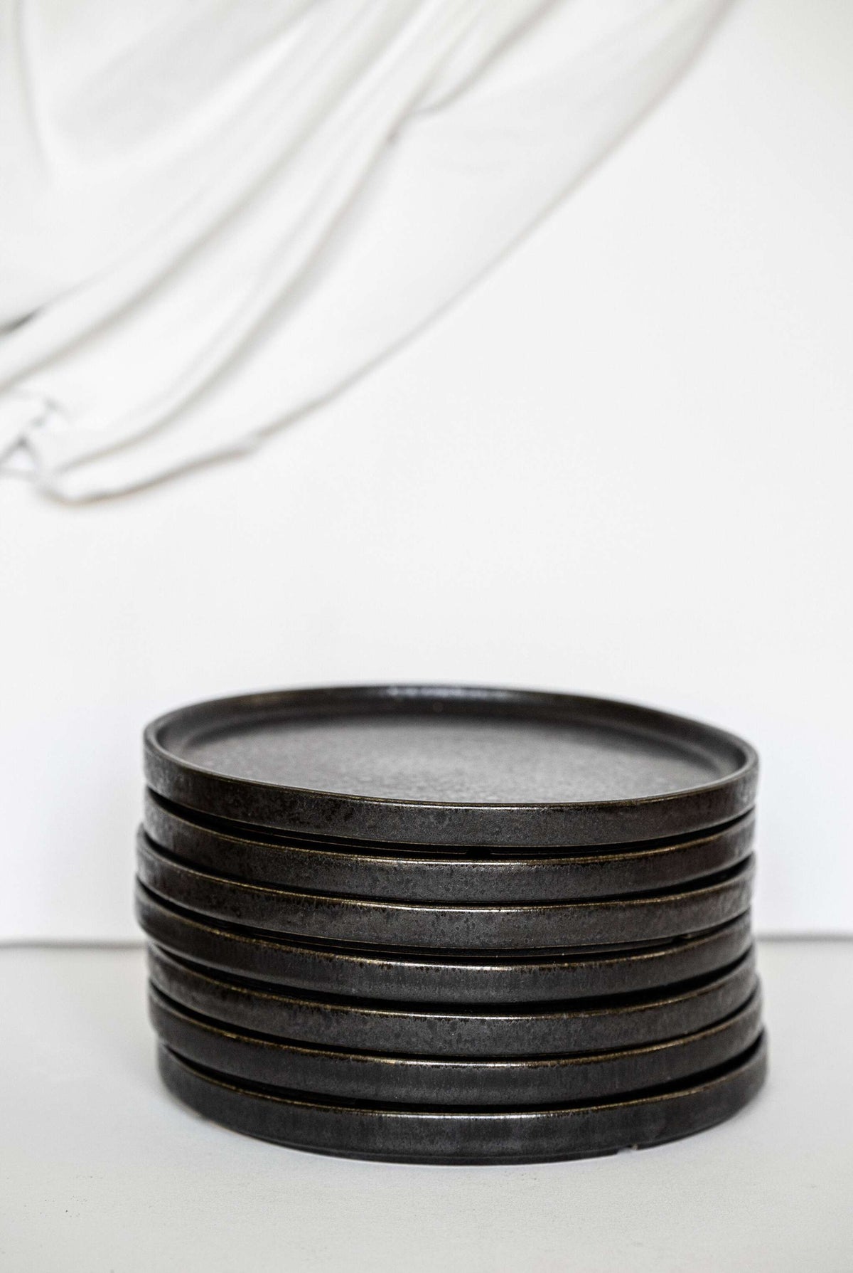 Black stoneware dinner plates with glossy speckled glaze and low edges