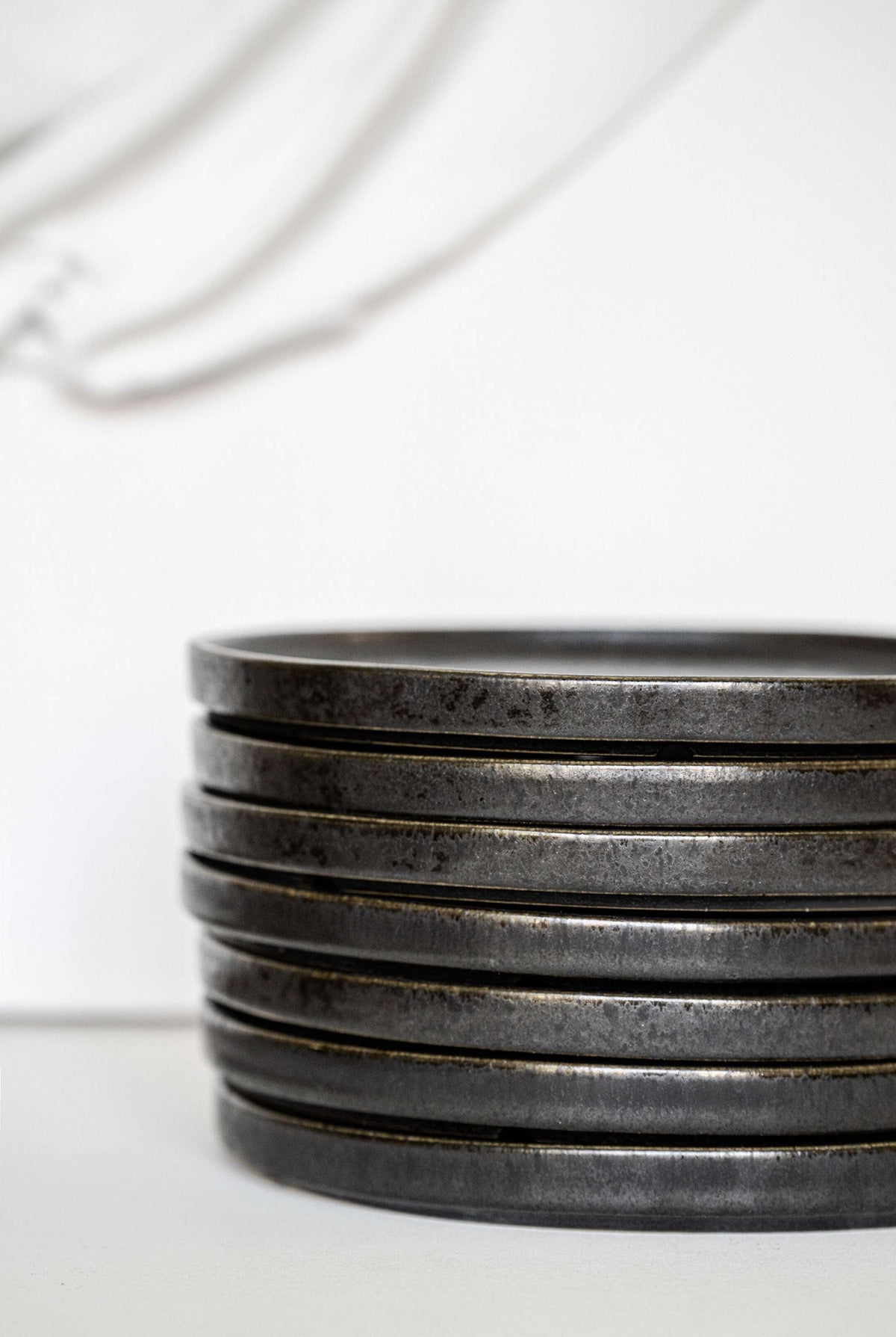 Black stoneware dinner plates with glossy speckled glaze and organic rims