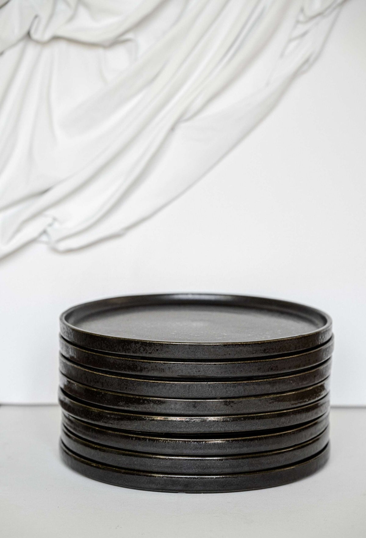 Black stoneware dinner plates with glossy speckled glaze and organic rims