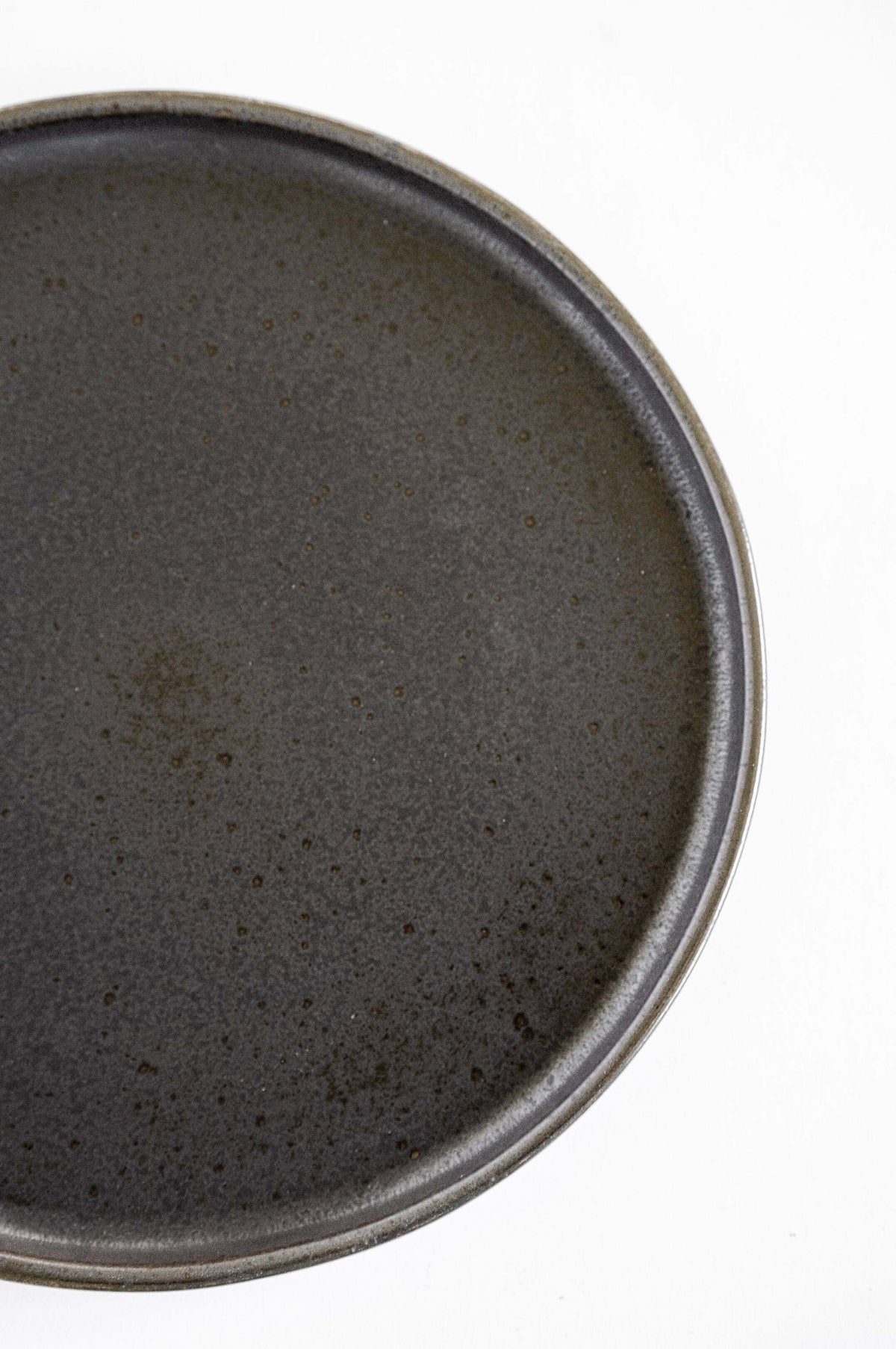 Black stoneware dinner plates with glossy speckled glaze and organic rims on a table setting