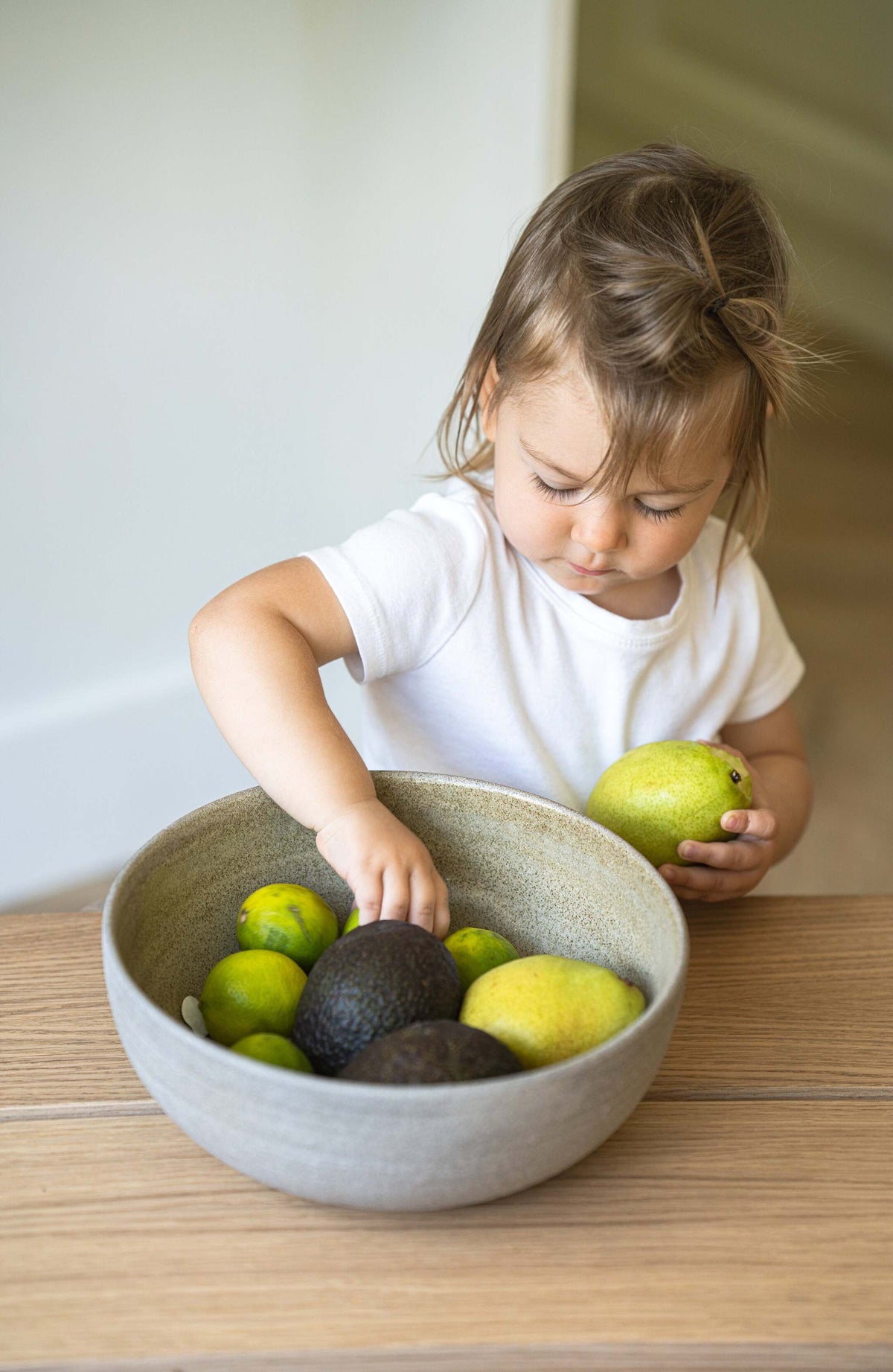 Stoneware large fruit bowl with polished concrete-like exterior and glossy interior glaze filled with fresh fruits