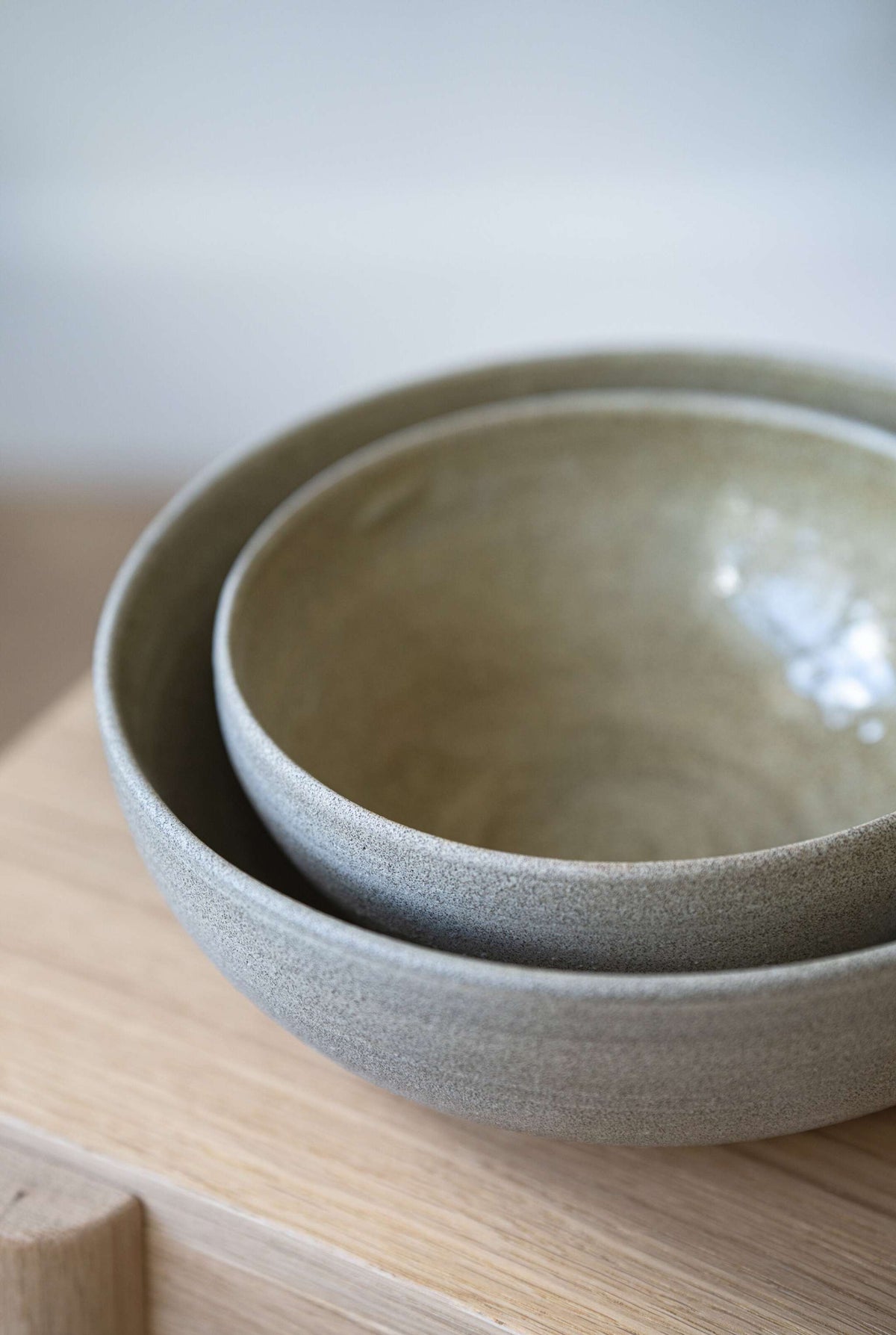 Large stoneware fruit bowl with concrete-style finish and glossy interior glaze on a kitchen table