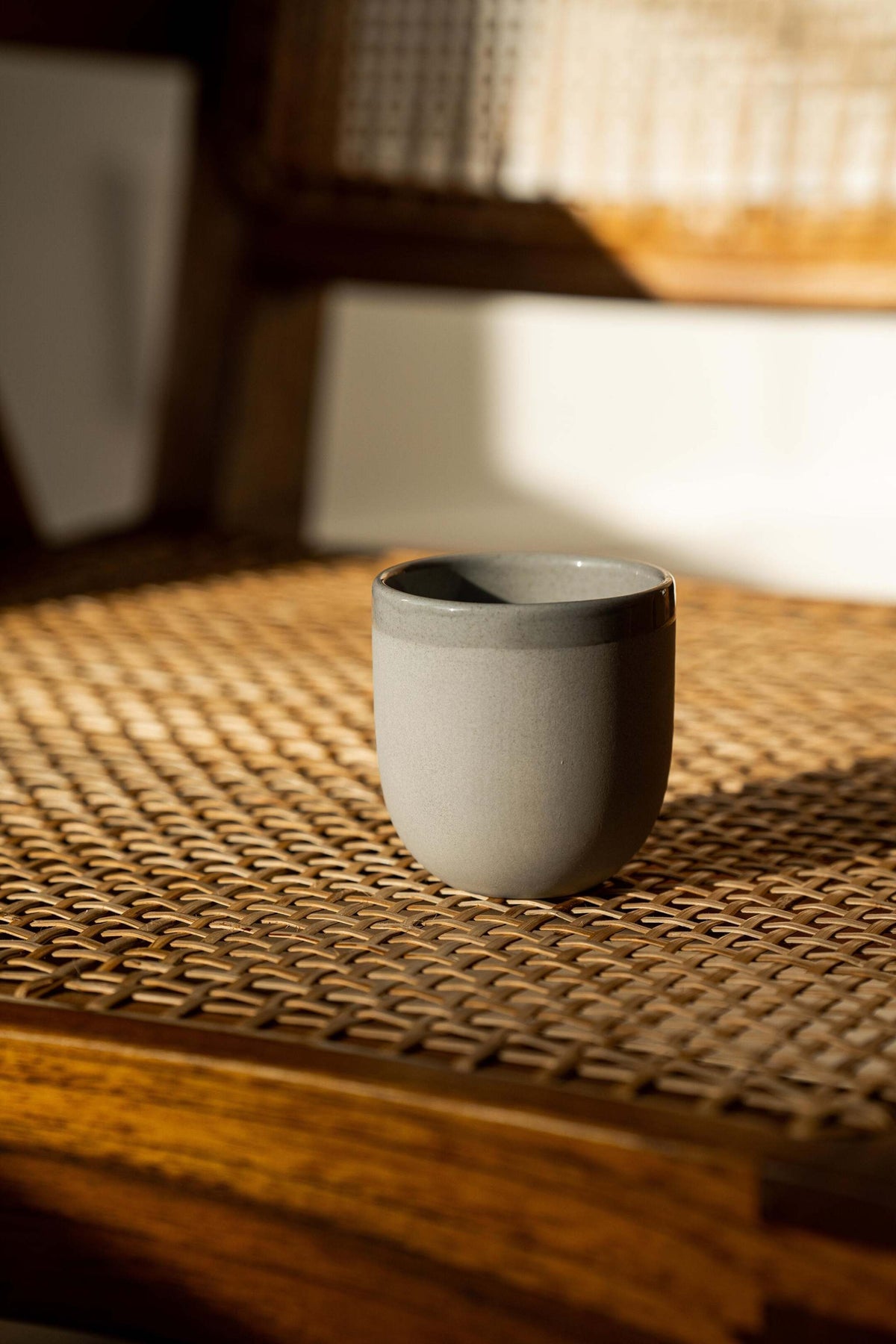 Handmade porcelain espresso cup with exposed clay exterior and glossy interior under gray sky