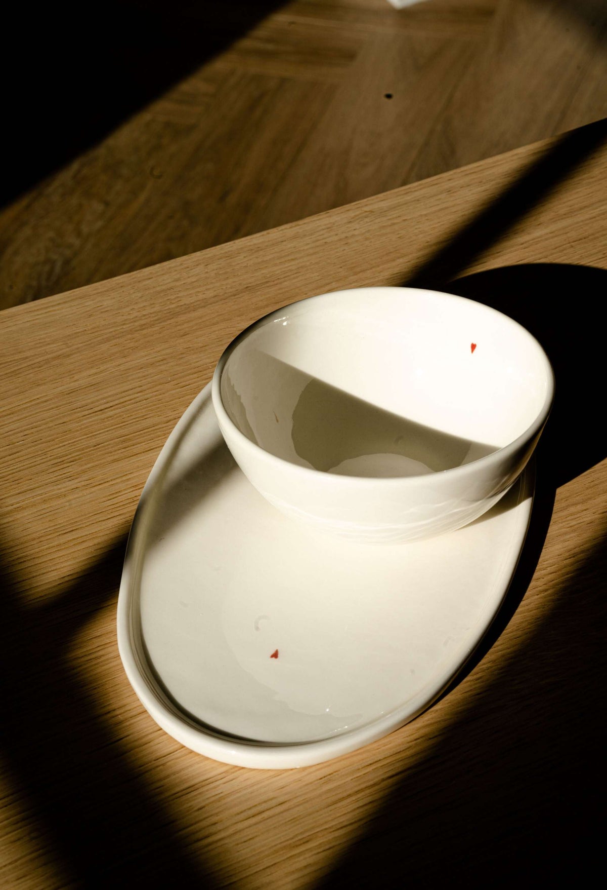 Handmade off-white porcelain bowl with glossy glaze and red heart detail