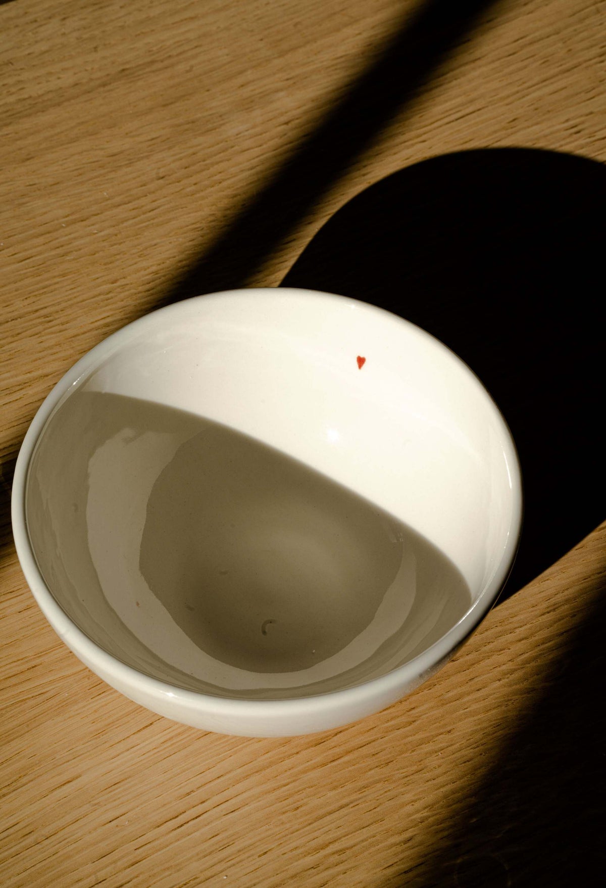 Handmade off-white porcelain bowl with glossy glaze and red heart detail