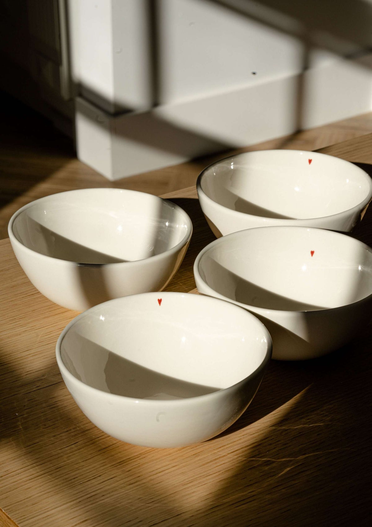 Off-white handmade porcelain bowl with shiny glaze and red heart detail