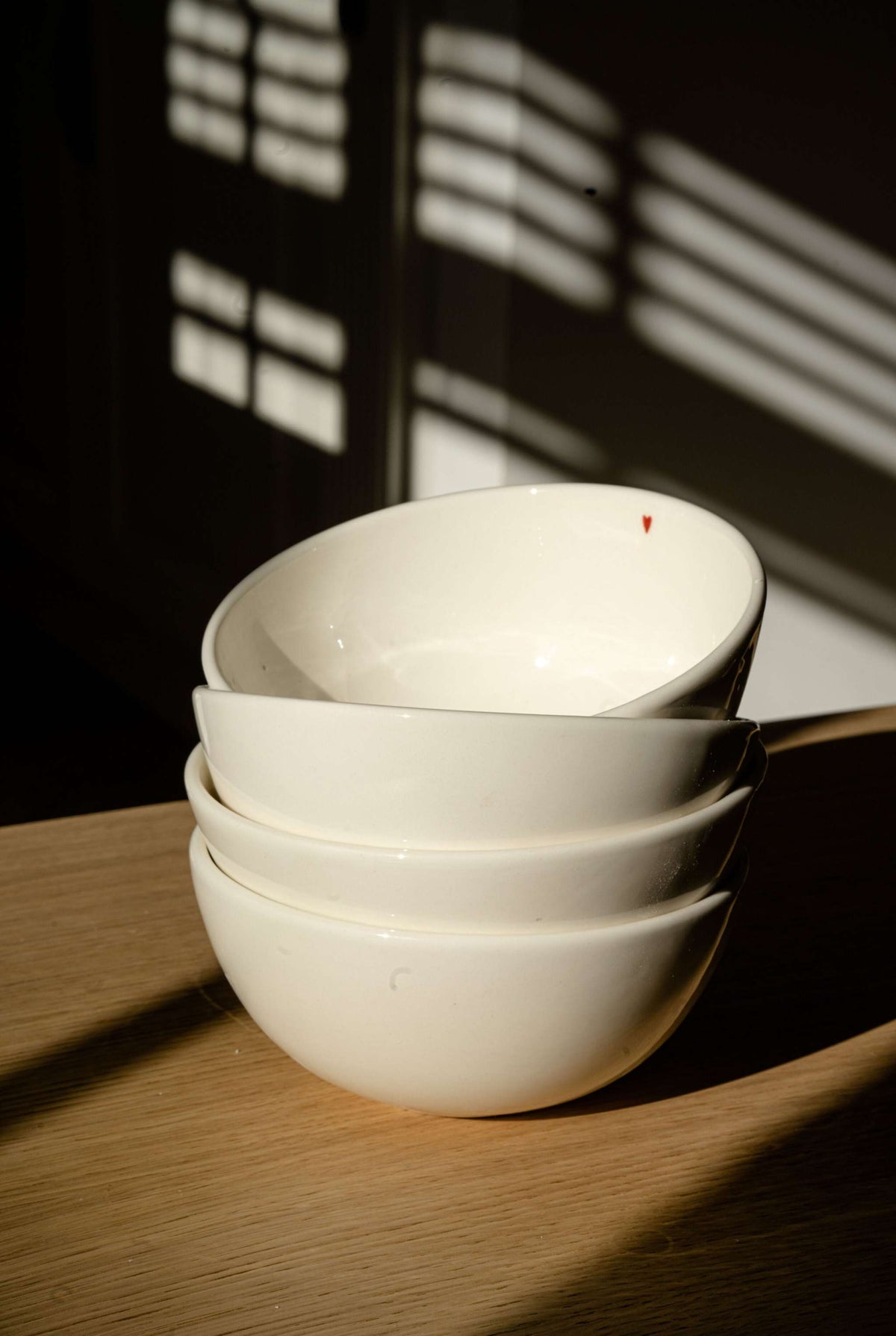 Off-white handmade porcelain bowl with shiny glaze and red heart detail