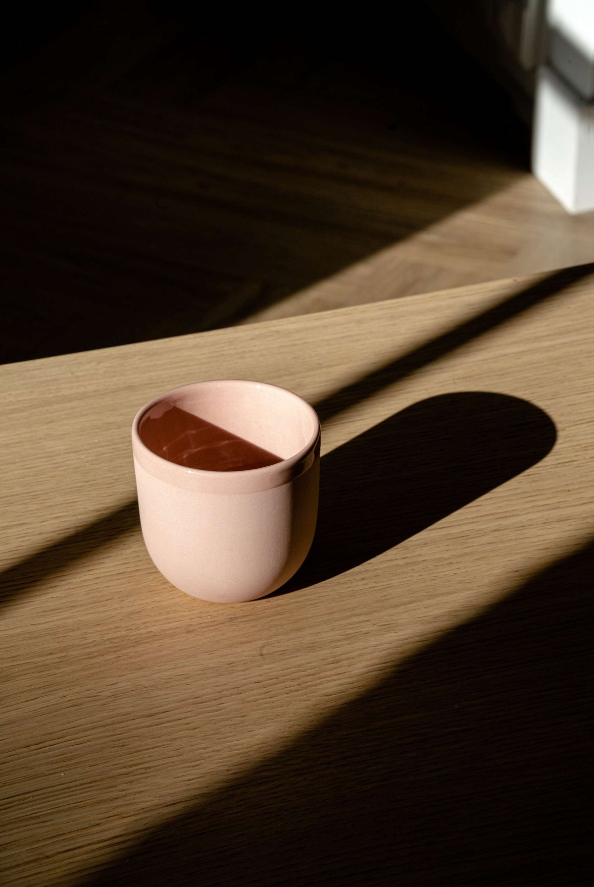 Handmade porcelain coffee cup in powder pink with glossy interior, smooth exterior, food-safe glaze, and lead-free materials.