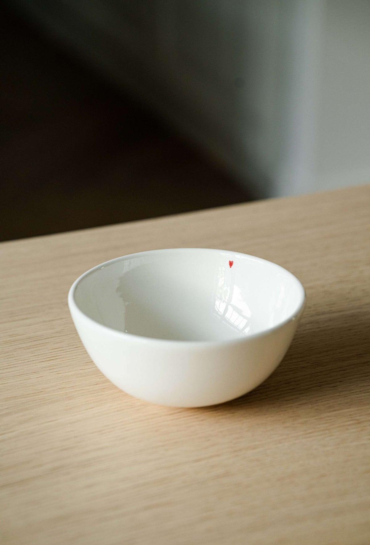 Handmade off-white porcelain bowl with shiny glaze and red heart detail