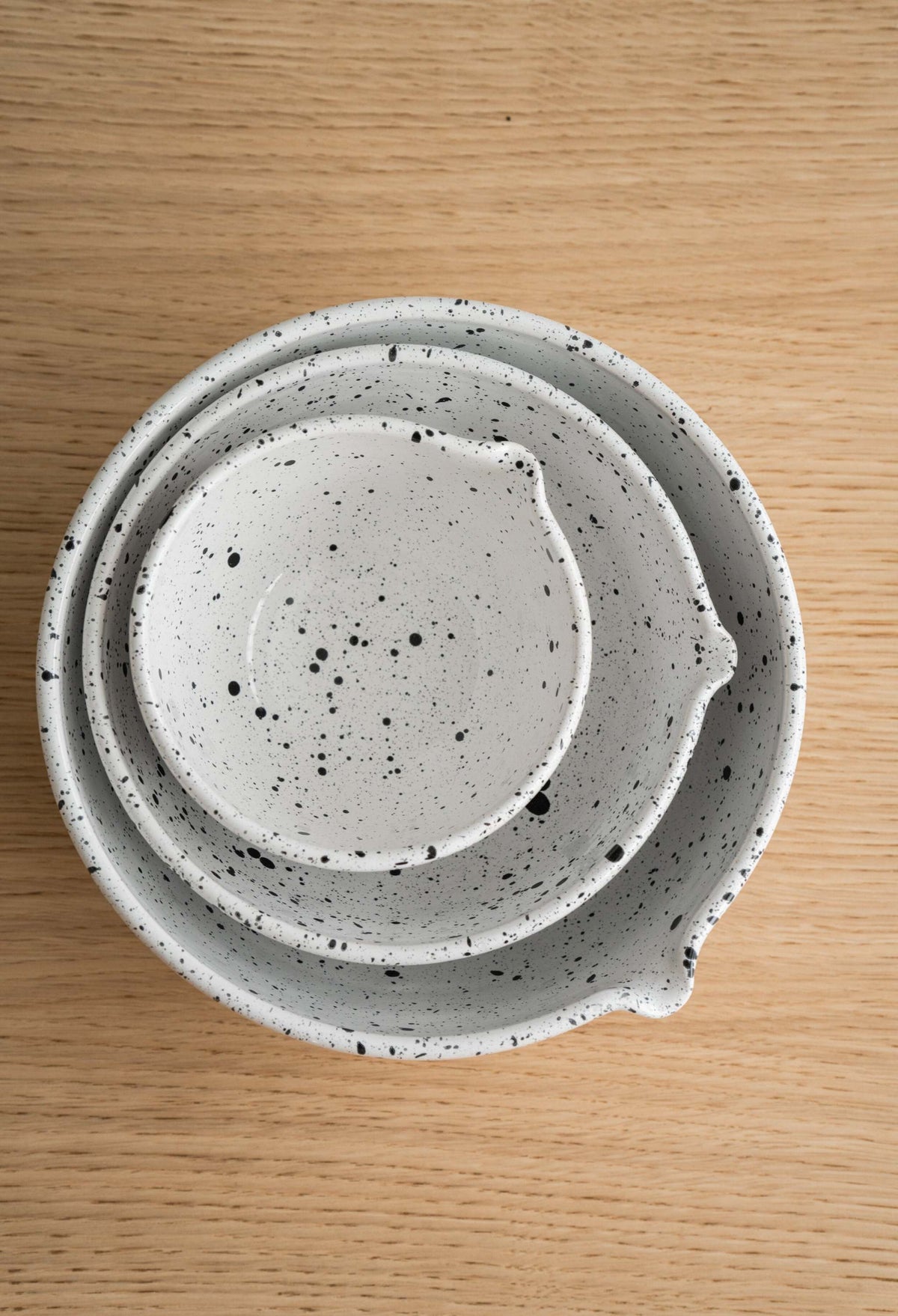 Deep stoneware mixing and serving bowls set with pour spouts and artisanal speckled finish nesting together.