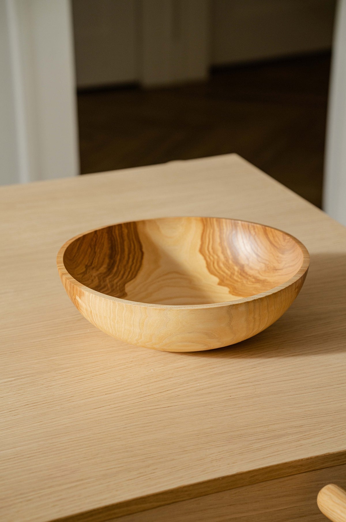 Wooden nesting bowl set with a single shallow golden-brown bowl, hand-carved from wood with dramatic flowing grain.