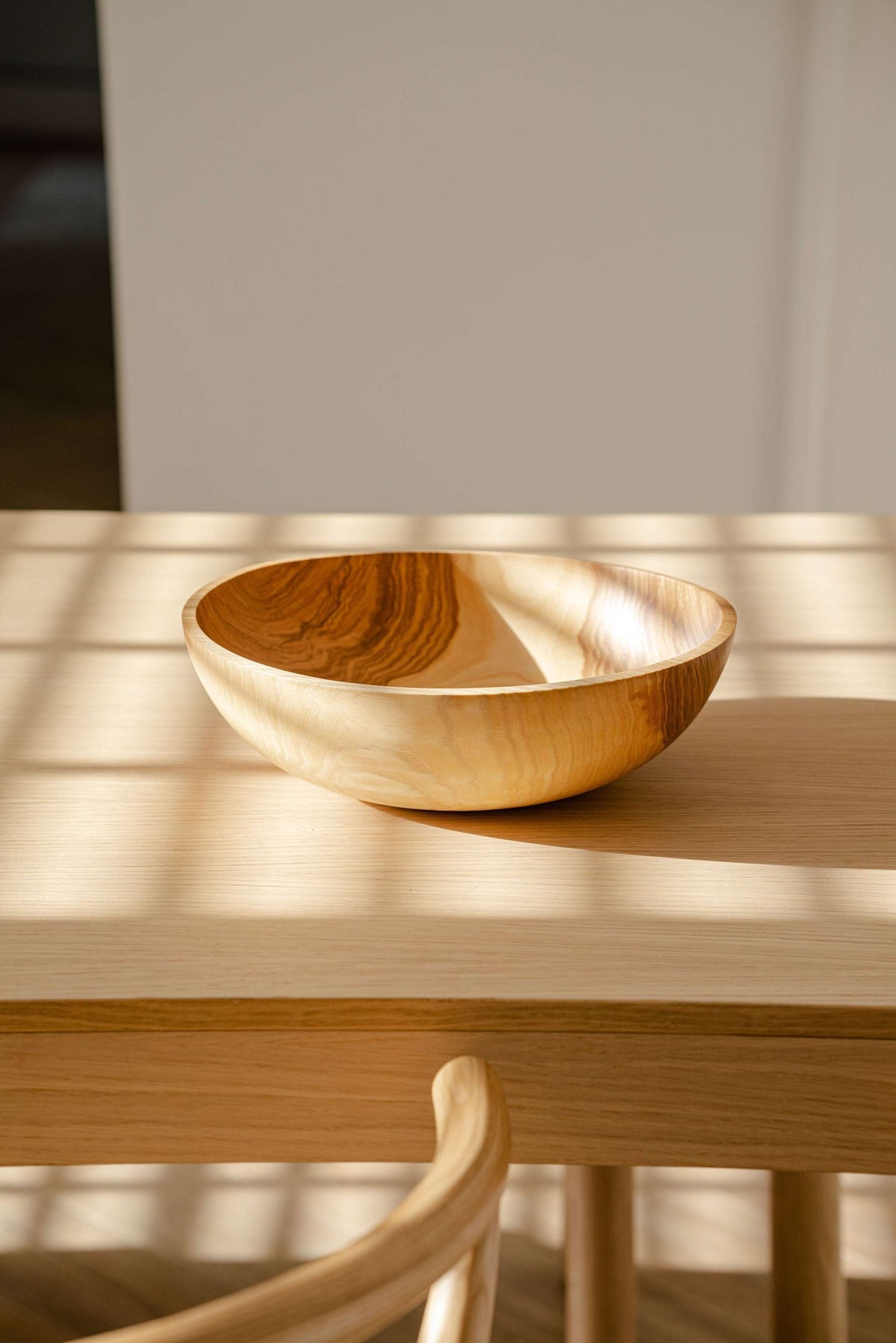 Wooden bowl in a warm honey-brown wooden nesting bowl set, with smooth carved grain and an irregular oval shape.