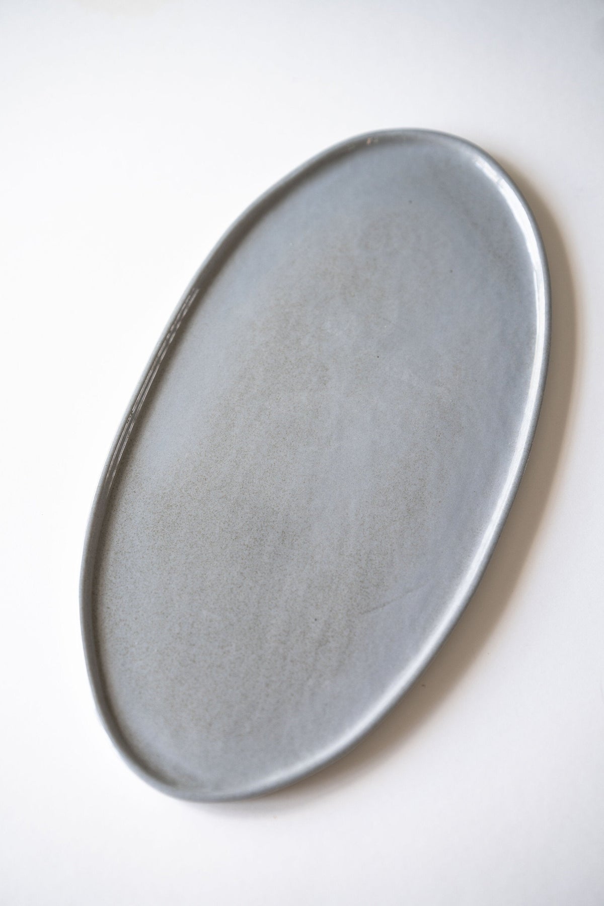 Handmade porcelain oval serving platter in gray sky color with organic edges, dishwasher-safe and food-safe glaze