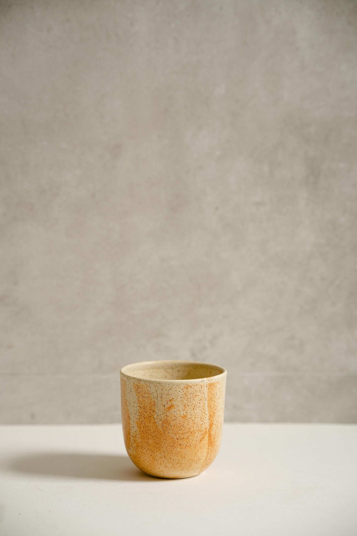 Handmade stoneware beige coffee cup with organic edges and unique reactive glaze swirl, 11 oz capacity, dishwasher and microwave safe.