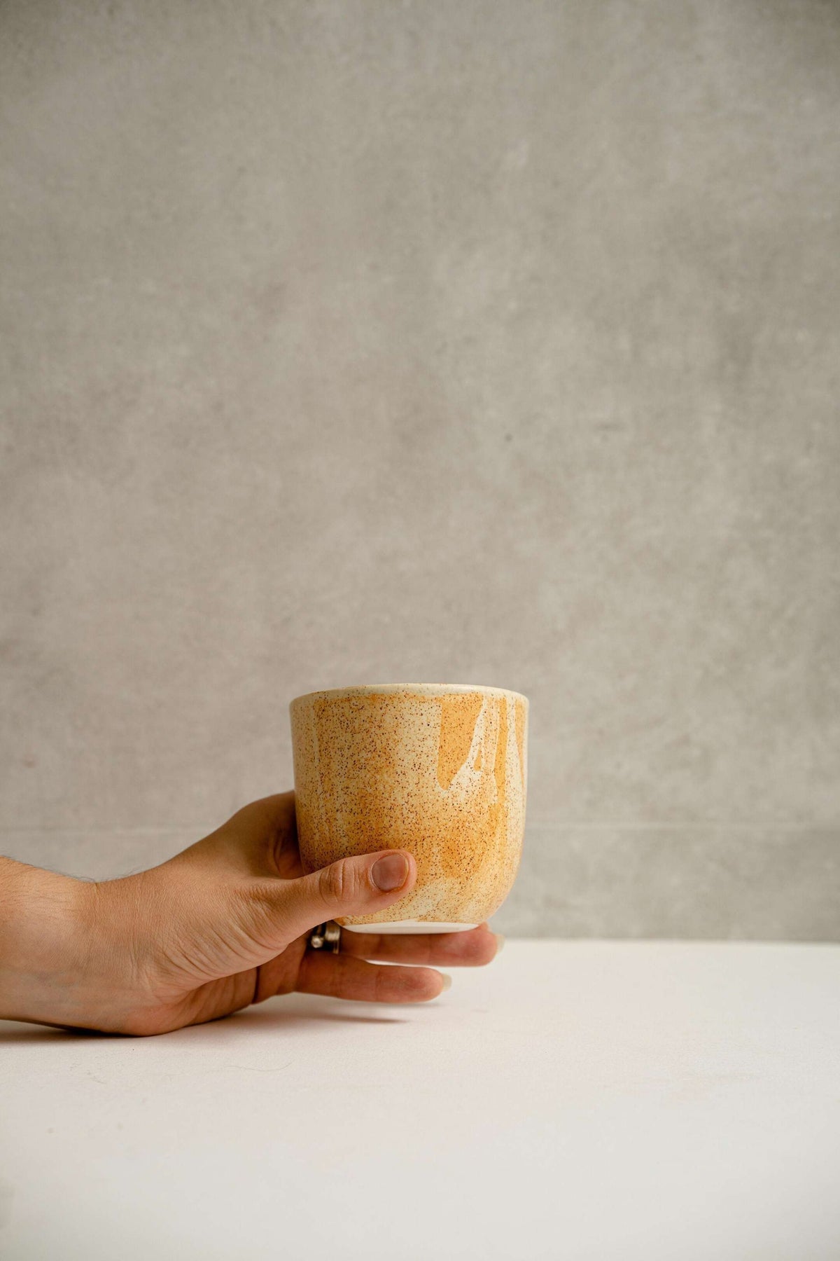 Handmade stoneware beige coffee cup with reactive glaze and rust drips, 11 oz, durable and microwave-safe