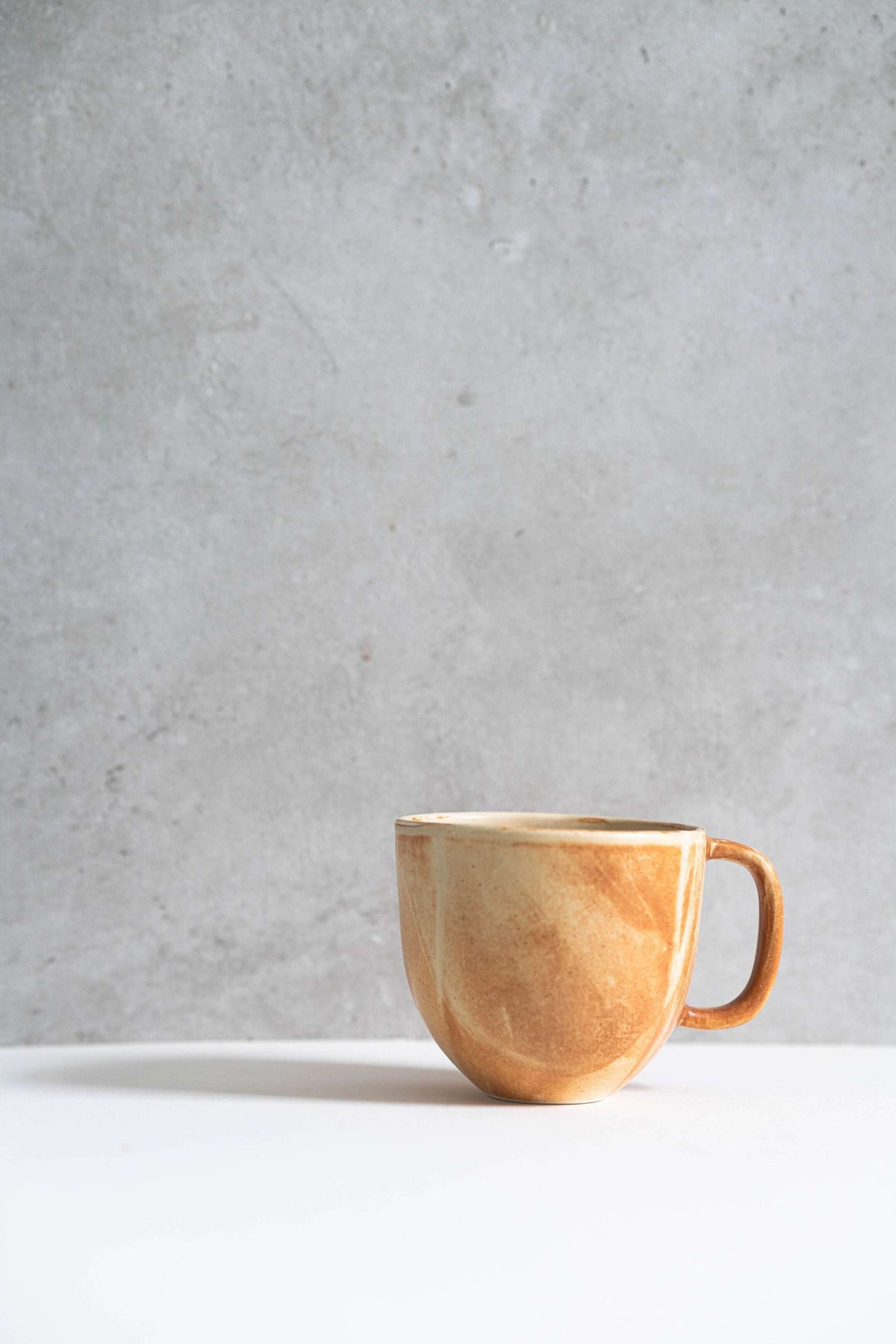 Stoneware beige coffee mug with organic edges and unique reactive glaze swirl pattern
