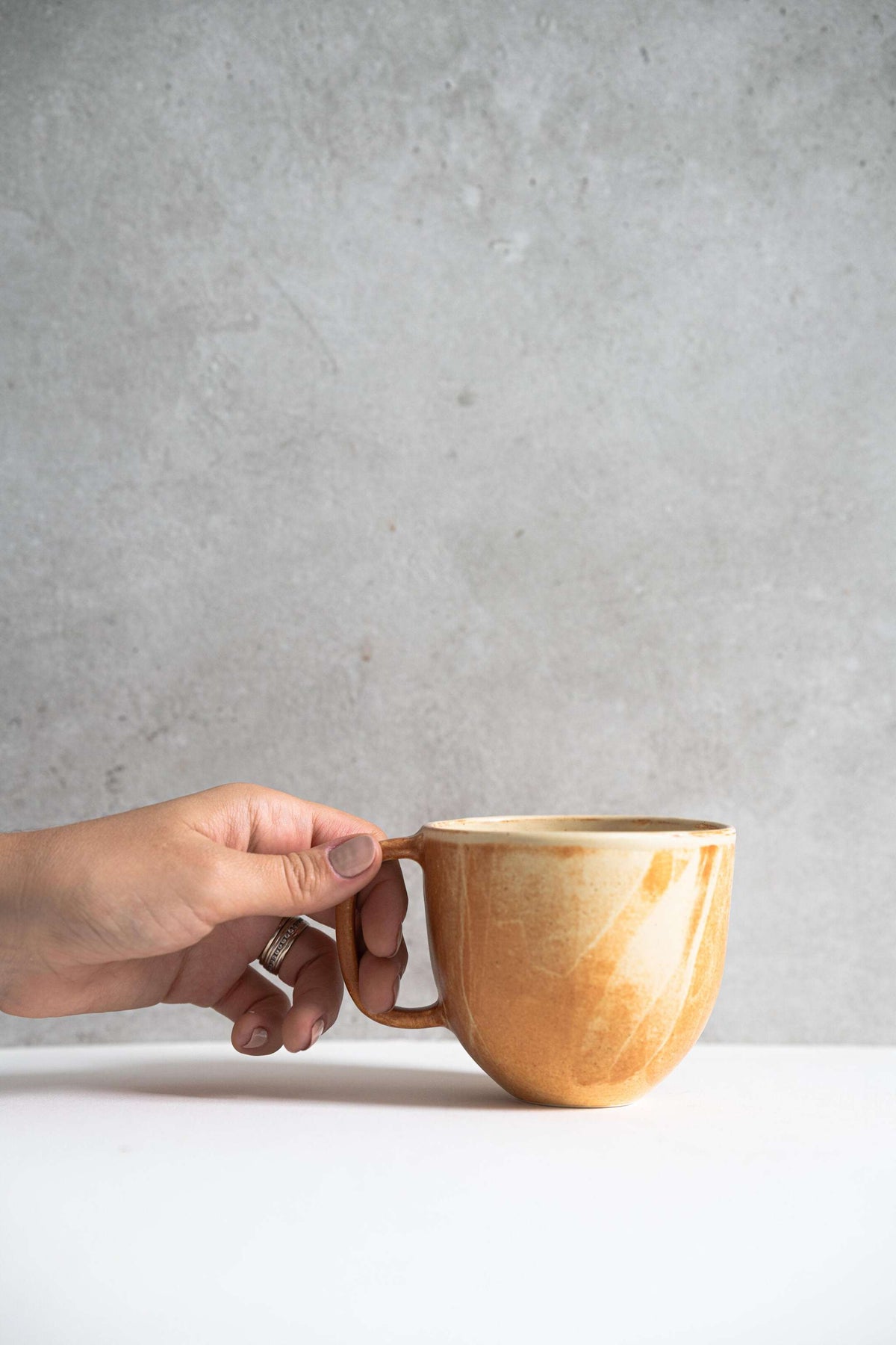 Stoneware beige coffee mug with organic edges and unique reactive glaze swirl