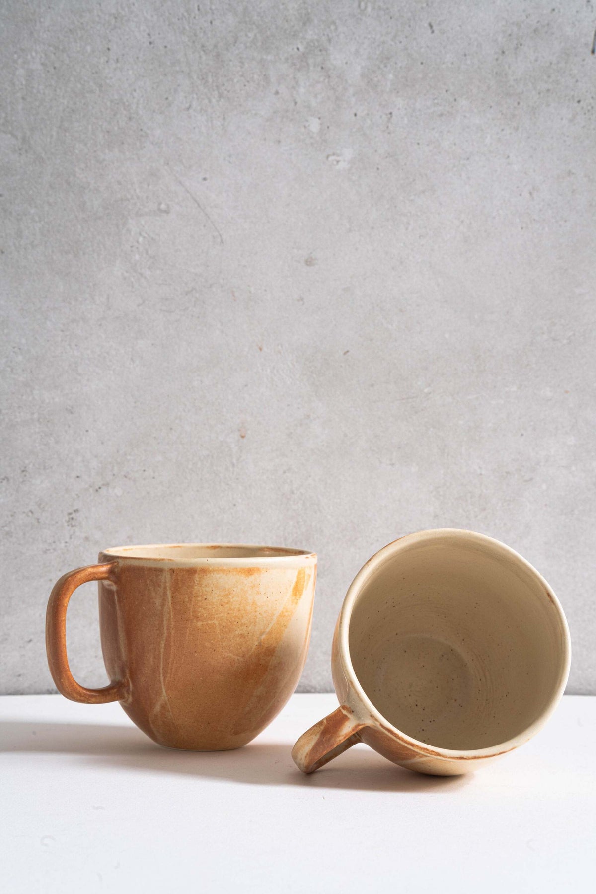 Handmade stoneware beige coffee mug with handle, organic edges, unique reactive glaze swirls and rust drips, microwave and dishwasher safe.