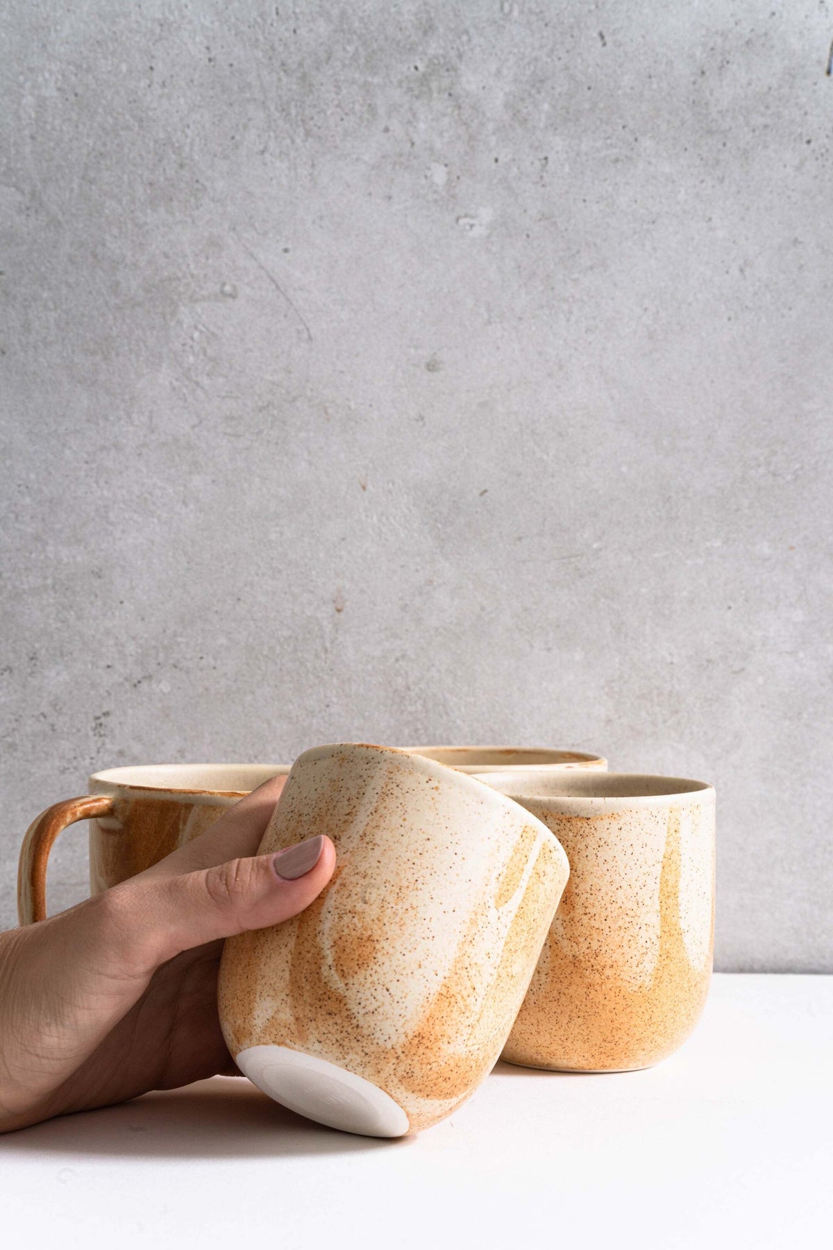 Handmade stoneware beige coffee cup with organic edges and reactive glaze swirl