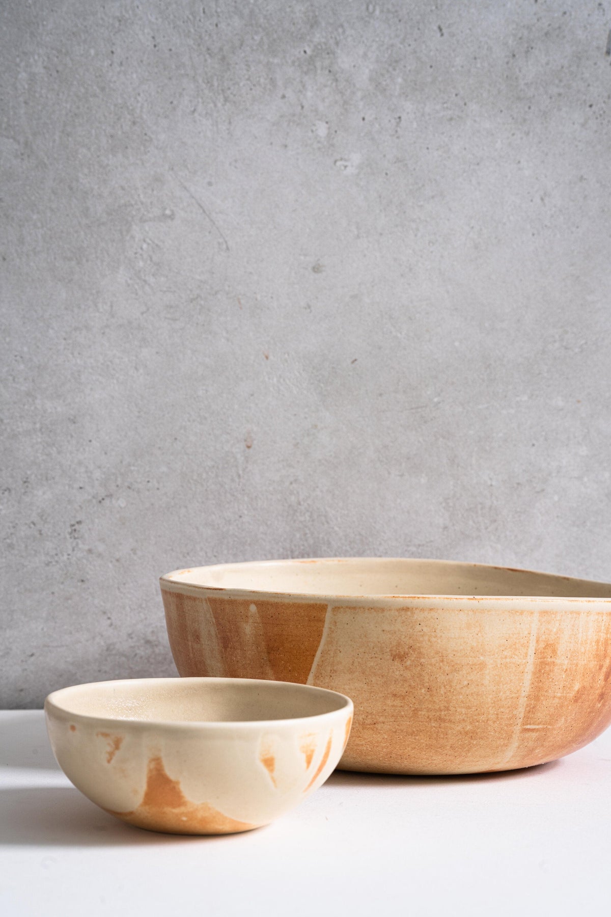 Beige matte stoneware salad serving bowl with hand-dipped reactive glaze and rust color strokes